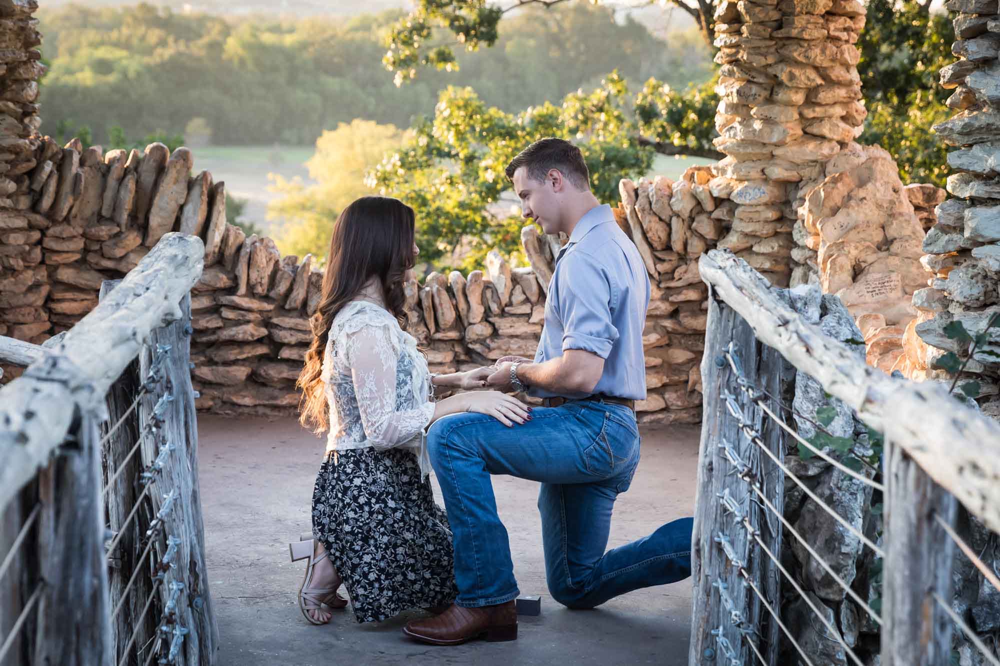Man proposing on one knee to woman in middle of stone building during Japanese Tea Garden surprise proposal by Kelly Williams San Antonio wedding photographer