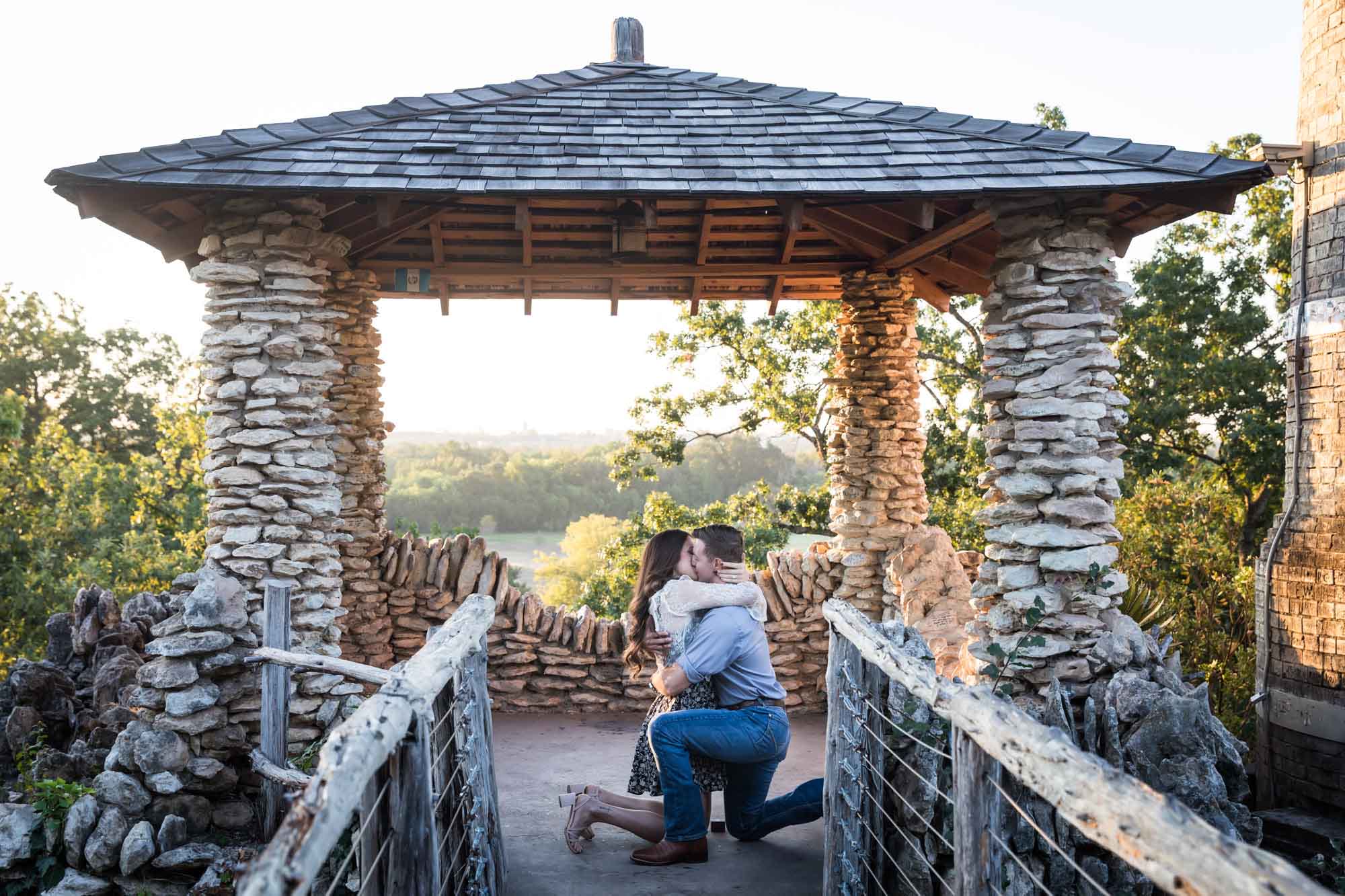 Man proposing on one knee to woman in middle of stone building during Japanese Tea Garden surprise proposal by Kelly Williams San Antonio wedding photographer