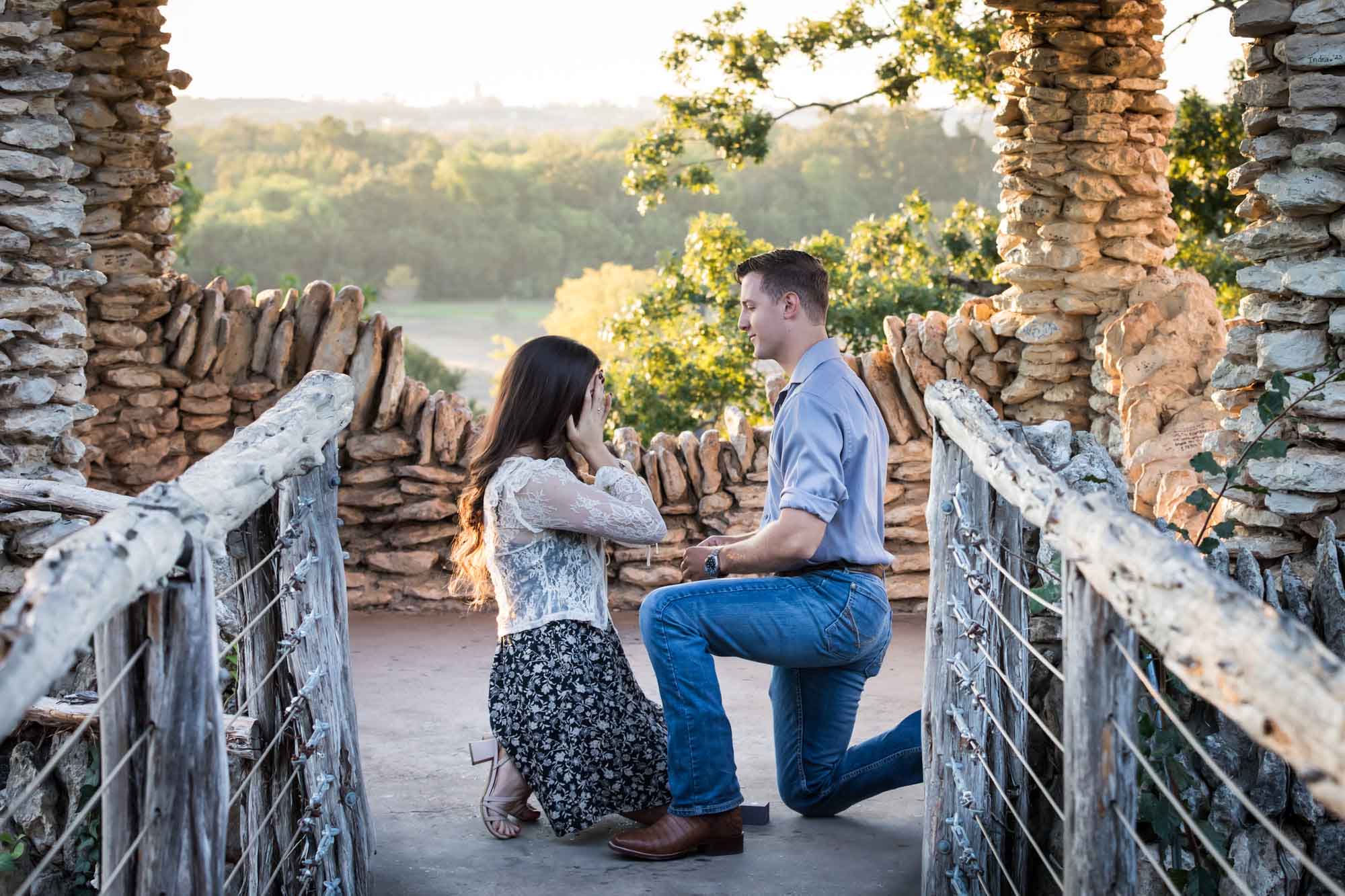 Man proposing on one knee to woman in middle of stone building during Japanese Tea Garden surprise proposal by Kelly Williams San Antonio wedding photographer