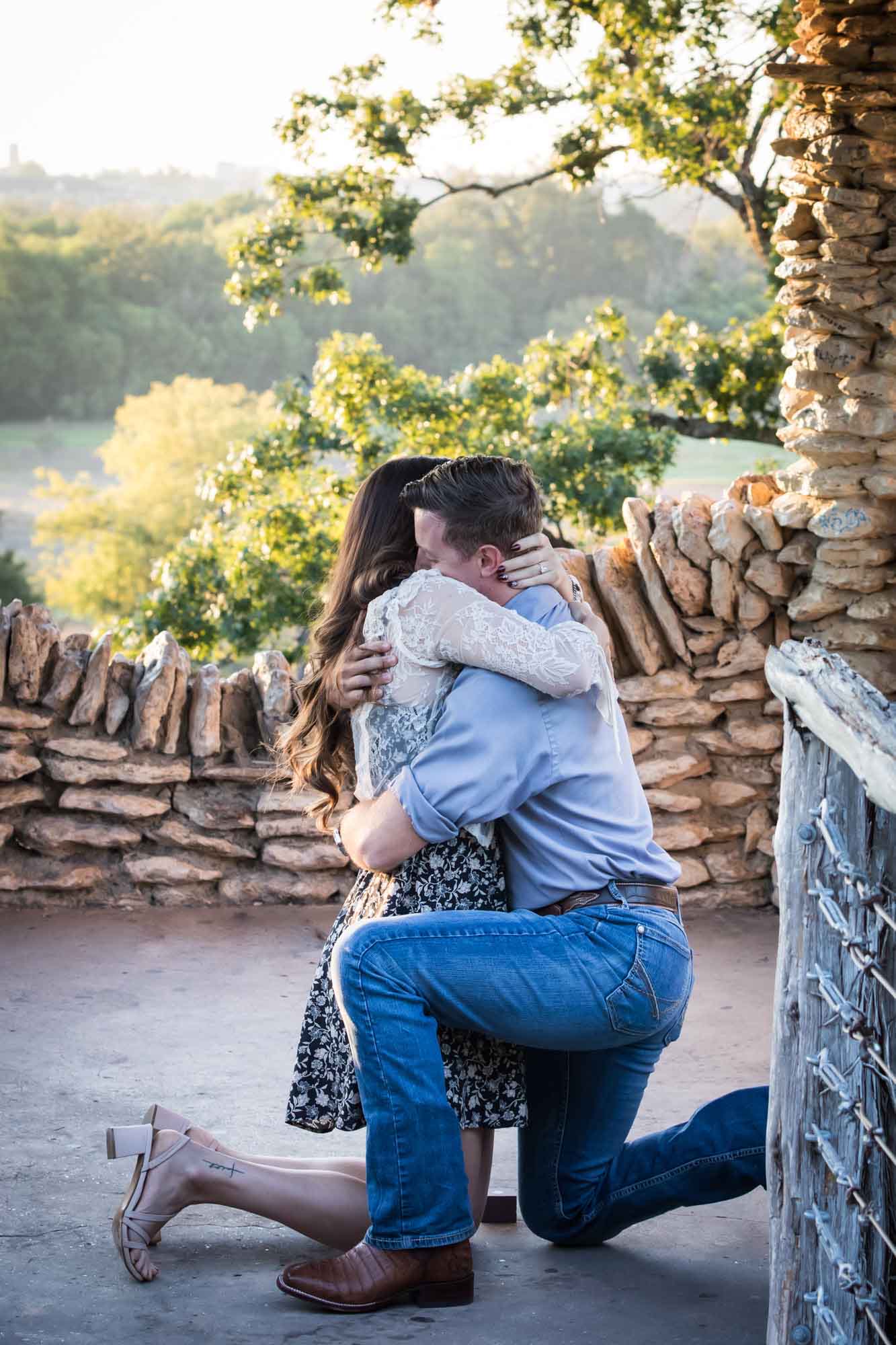 Man proposing on one knee to woman in middle of stone building during Japanese Tea Garden surprise proposal by Kelly Williams San Antonio wedding photographer