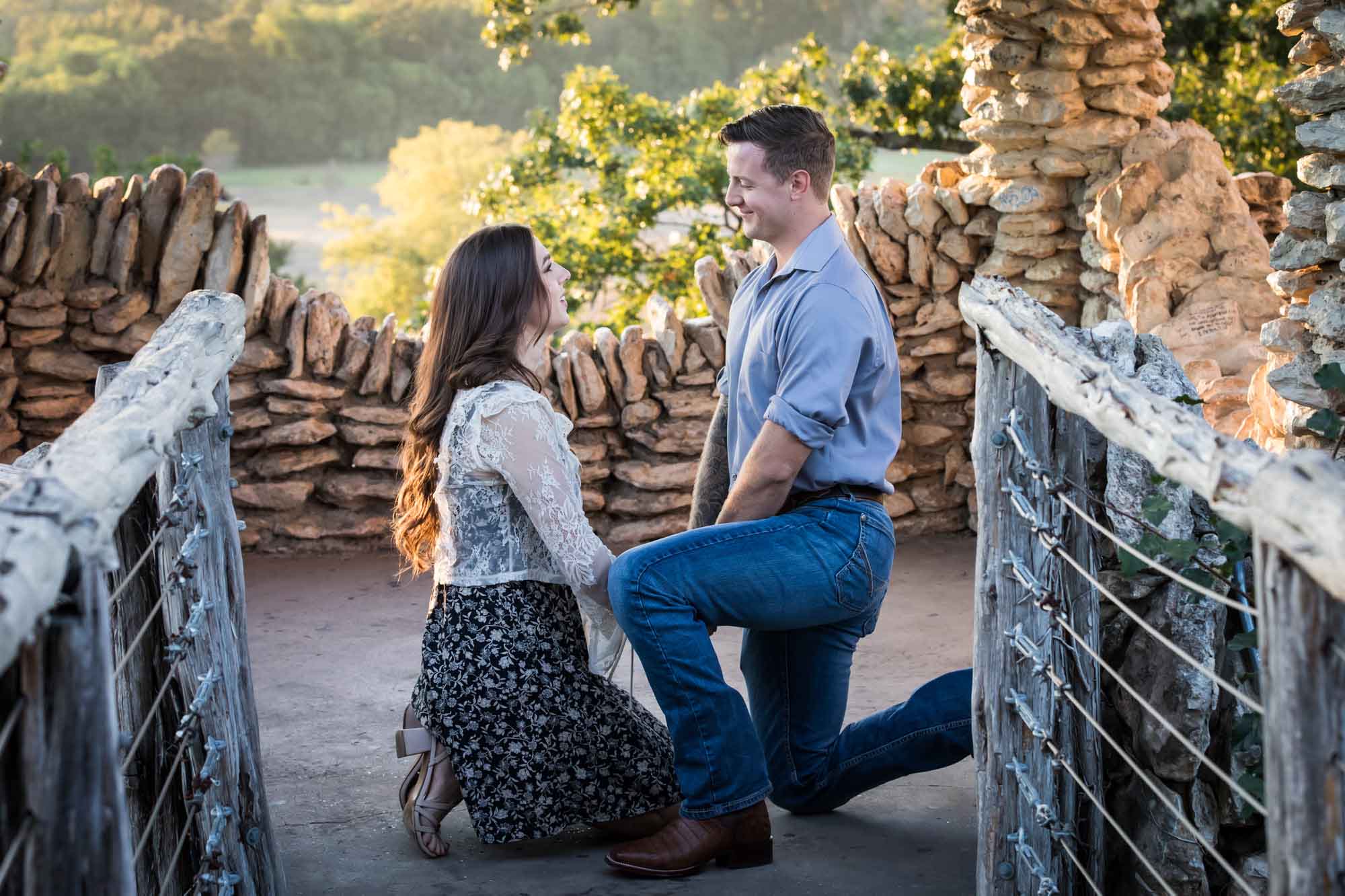 Man proposing on one knee to woman in middle of stone building during Japanese Tea Garden surprise proposal by Kelly Williams San Antonio wedding photographer