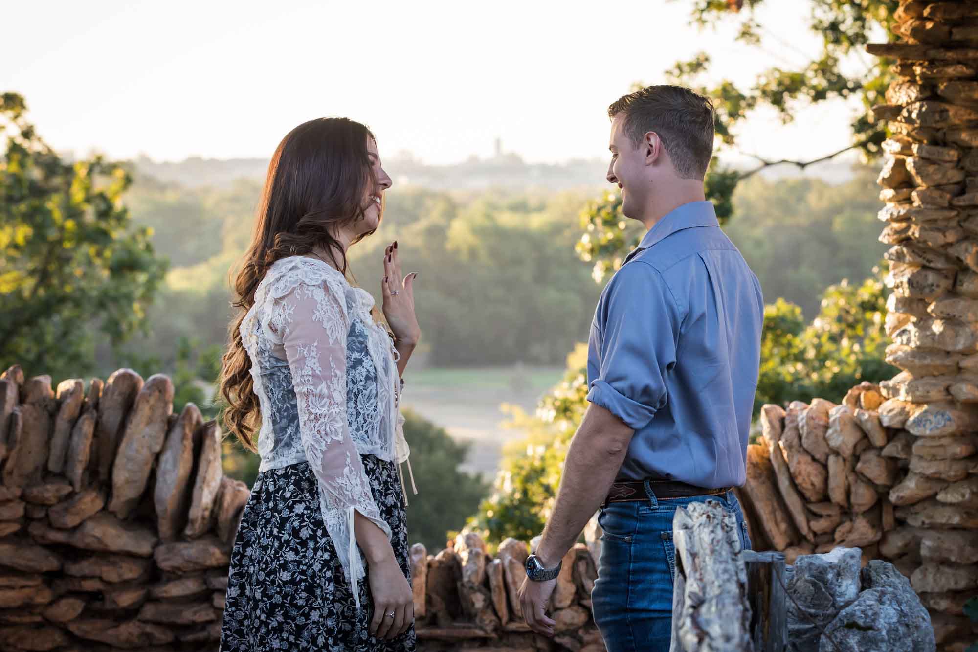 Couple looking at engagement ring on woman's hand in middle of stone building during a Japanese Tea Garden engagement portrait 