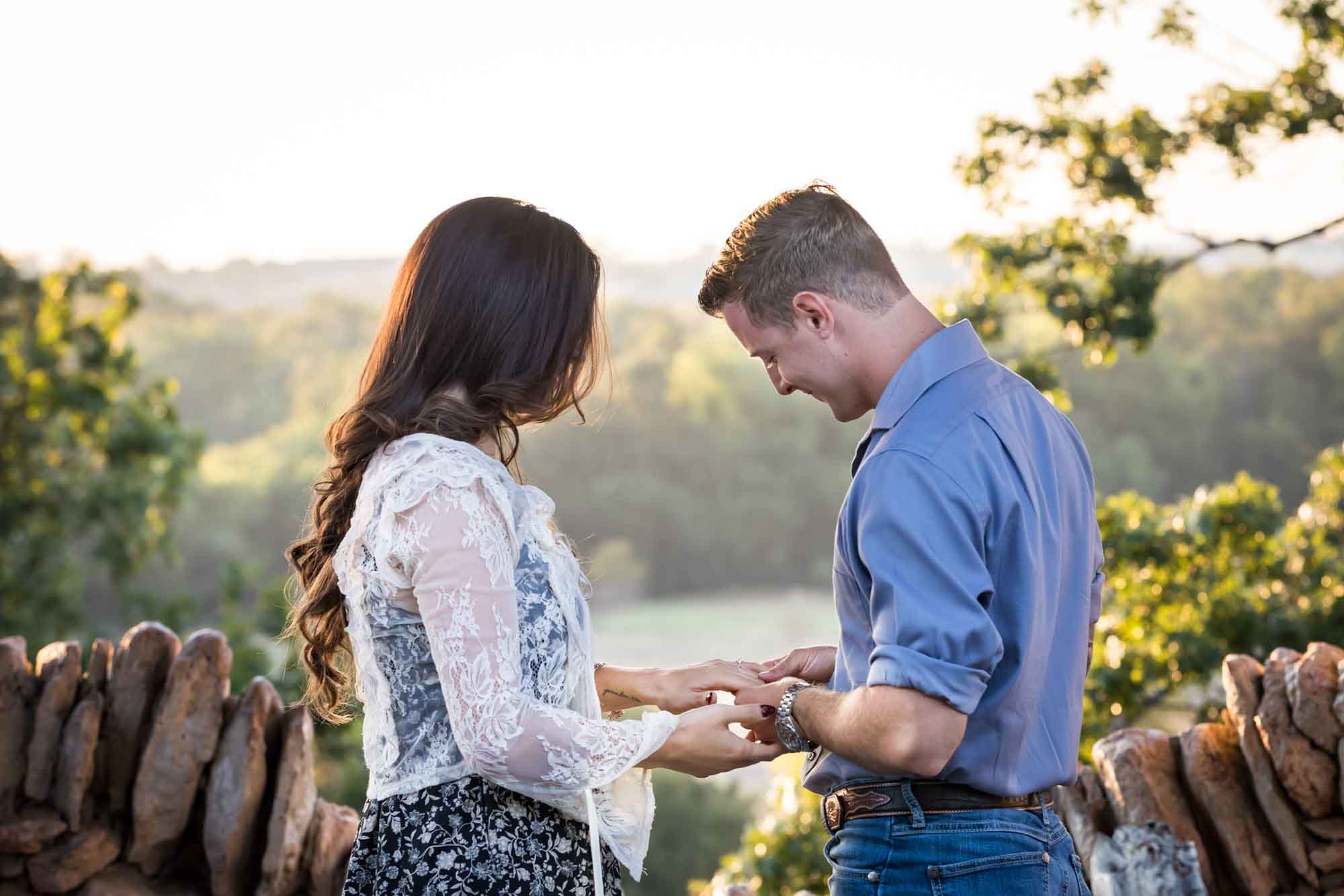 Couple looking at engagement ring on woman's hand in middle of stone building during a Japanese Tea Garden engagement portrait 