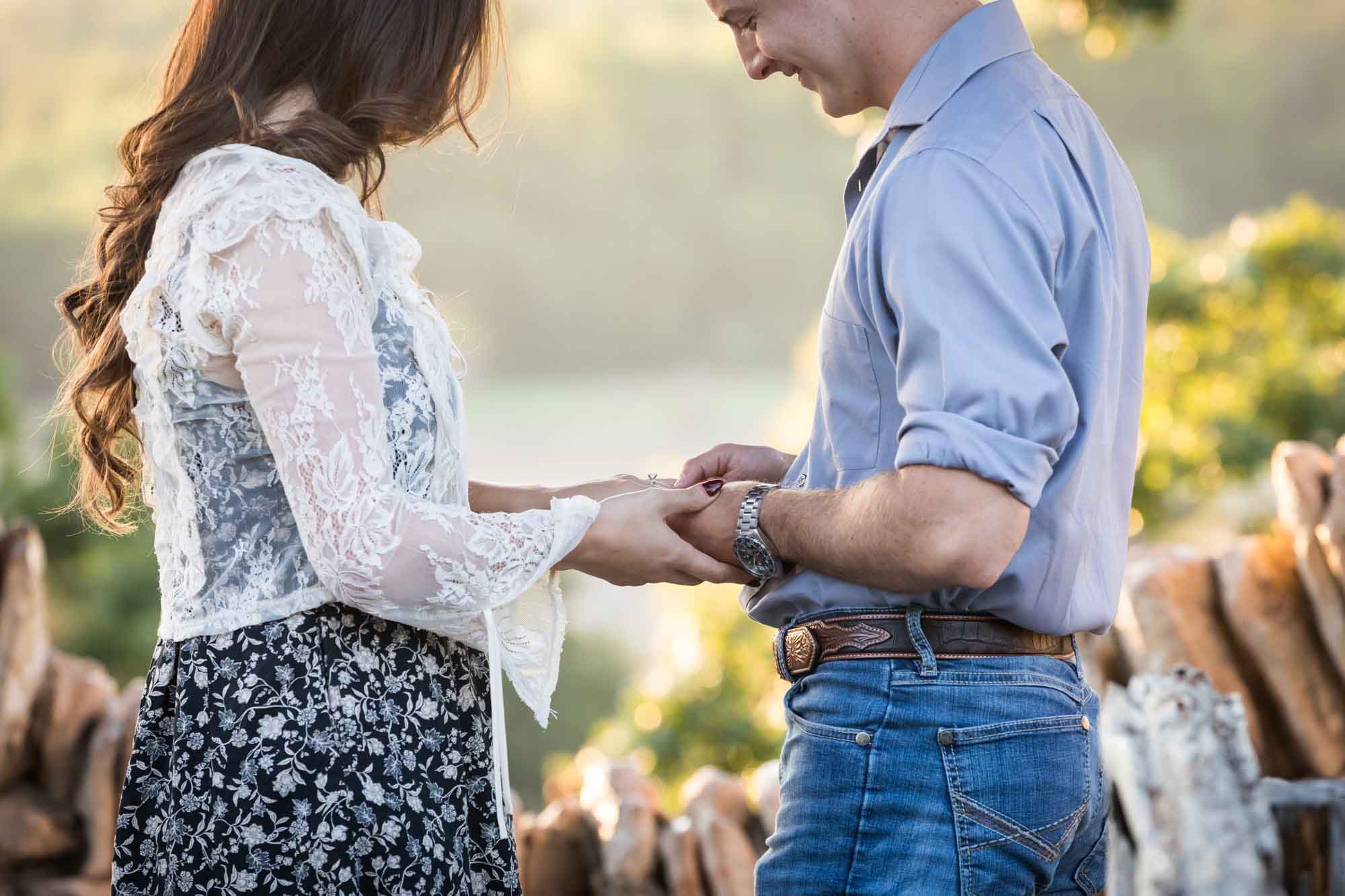 Couple looking at engagement ring on woman's hand in middle of stone building during a Japanese Tea Garden engagement portrait 