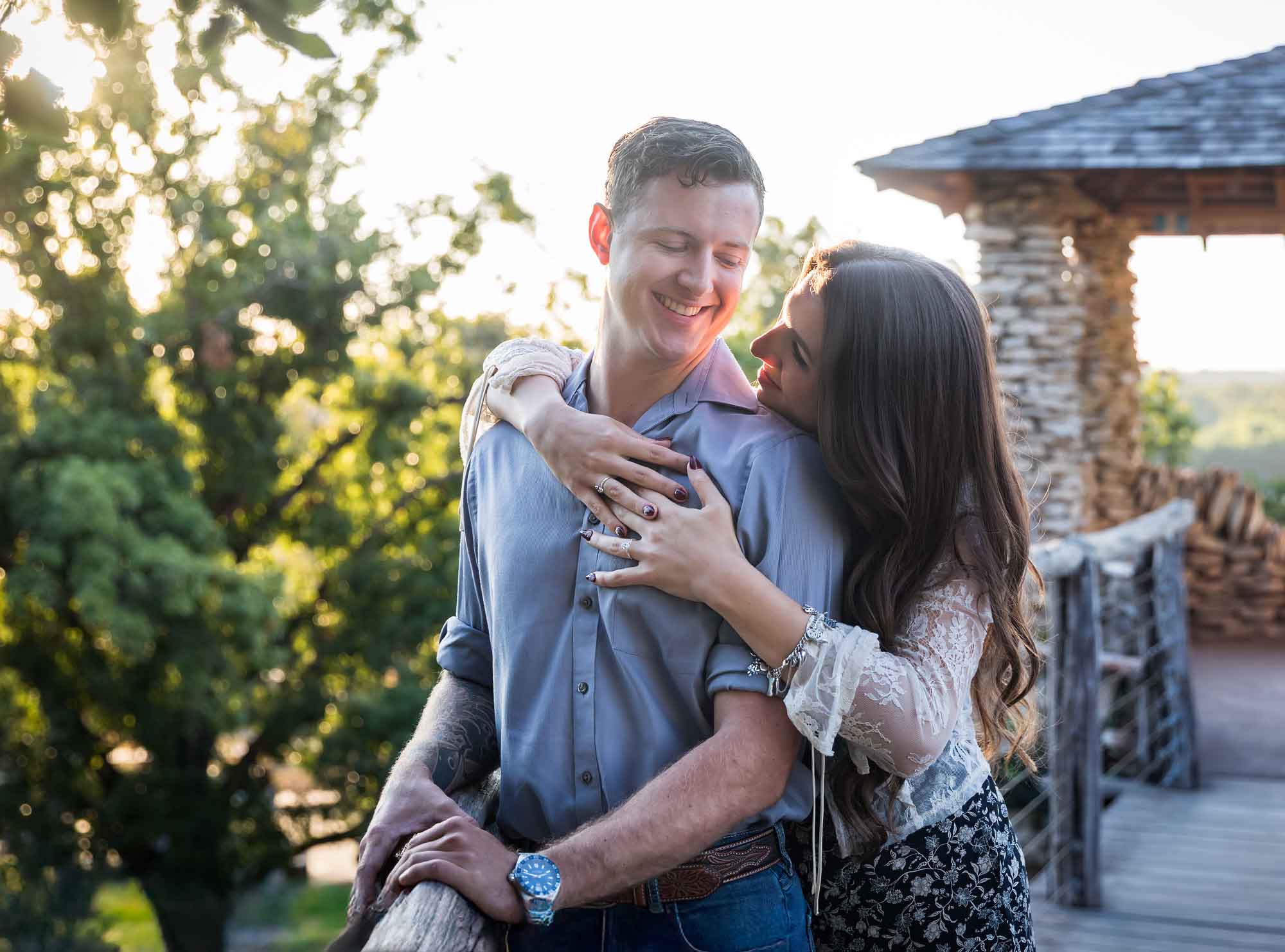 Couple hugging in front of stone building on wooden platform during a Japanese Tea Garden engagement portrait 