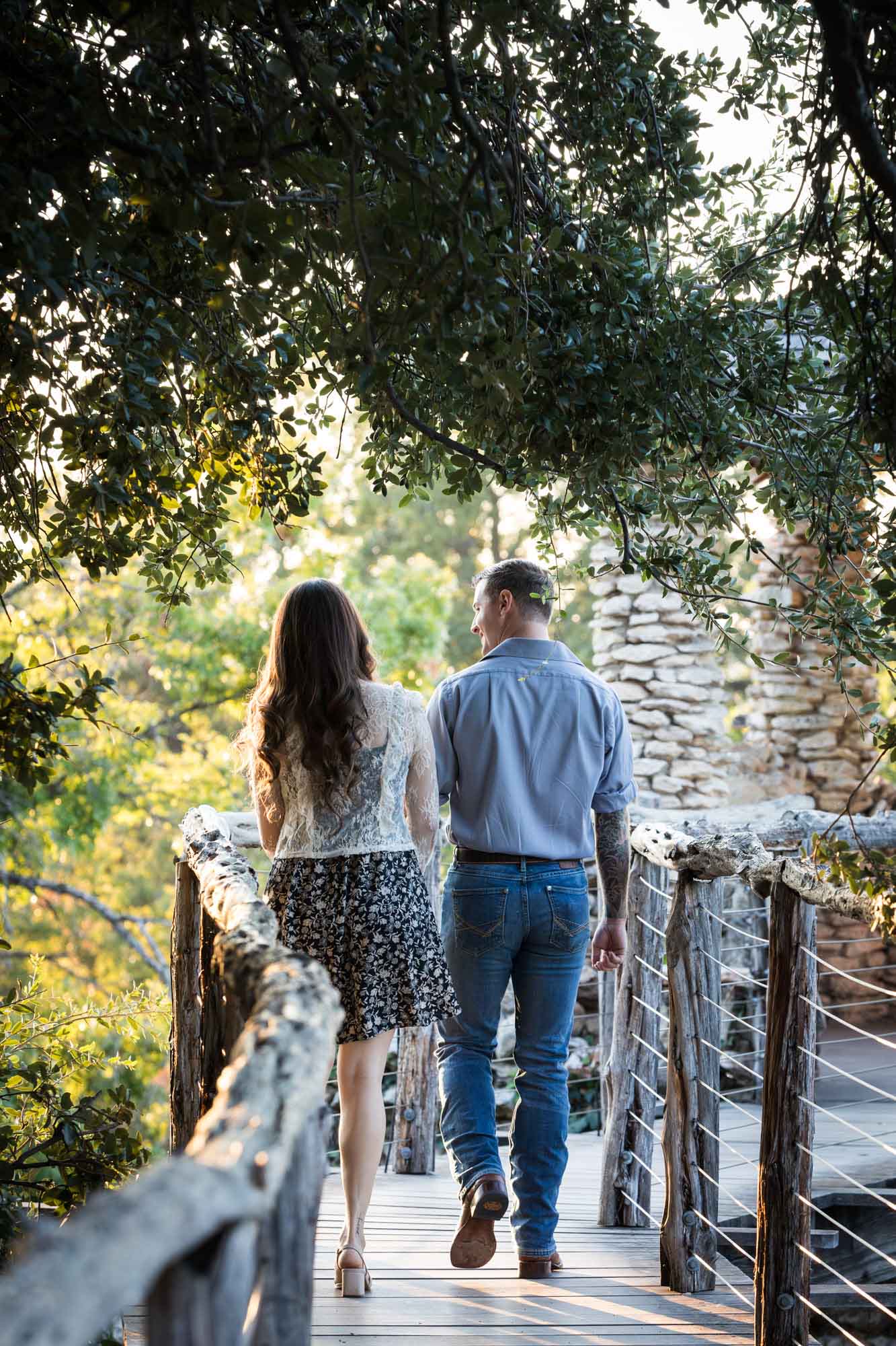 Couple walking along wooden pathway to stone building in Japanese Tea Garden for a surprise proposal