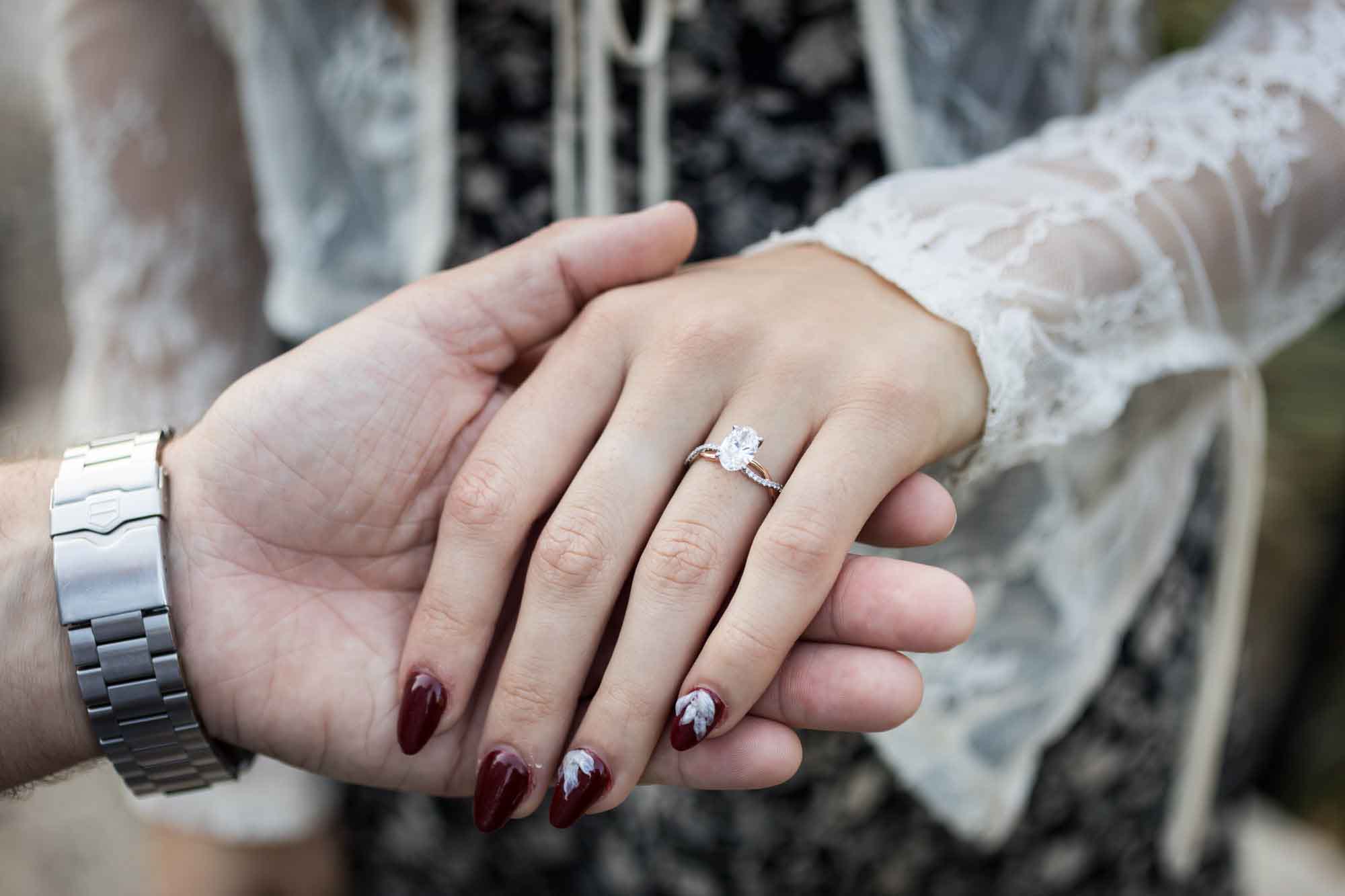 Close up of a man holding a woman's hand showing her wearing an engagement ring for an article on ‘Where do I Start with Wedding Planning?’