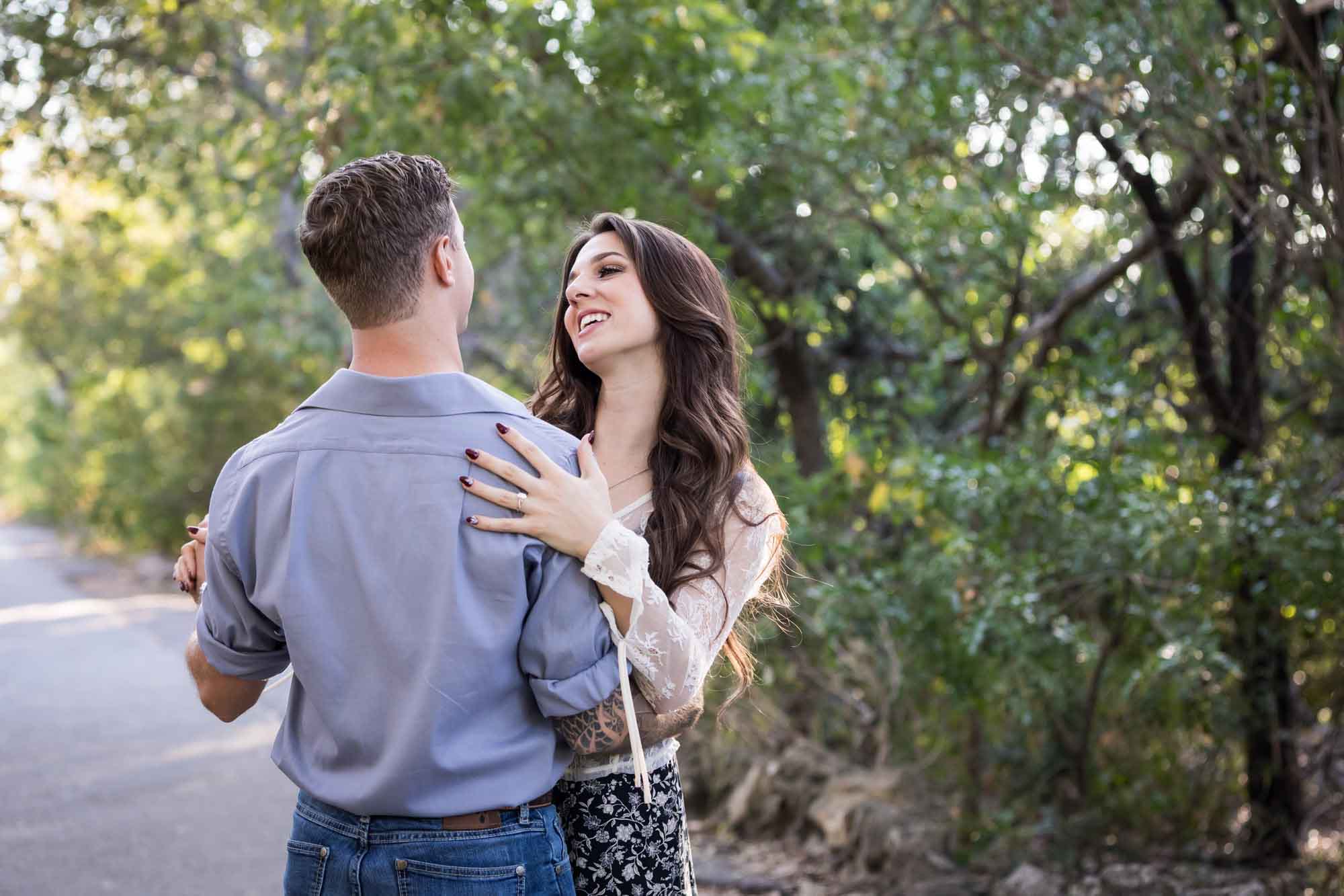 Couple dancing under tree branches in Brackenridge Park during a Japanese Tea Garden engagement portrait by San Antonio wedding photographer Kelly Williams