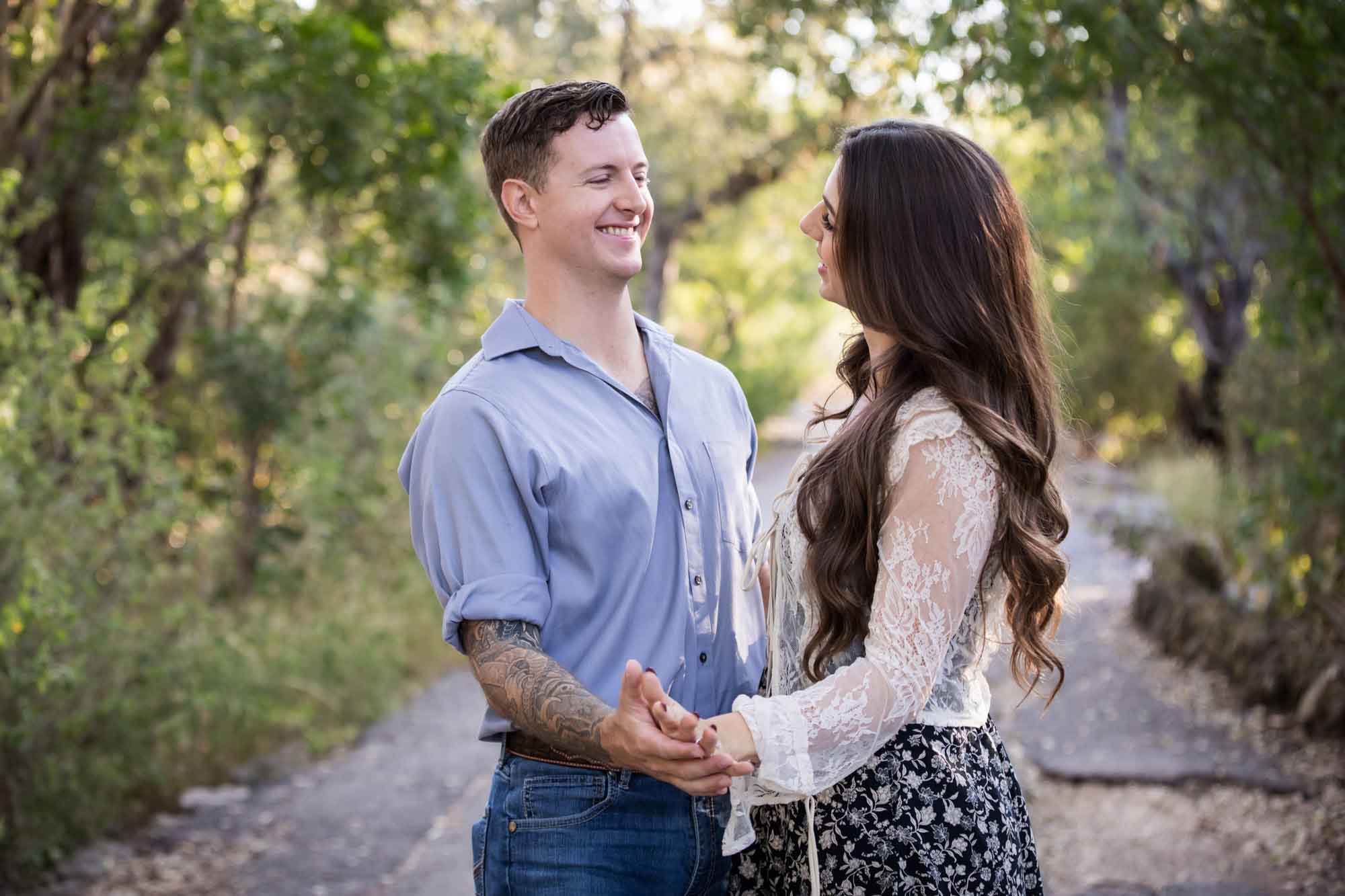 Couple dancing under tree branches in Brackenridge Park during a Japanese Tea Garden engagement portrait by San Antonio wedding photographer Kelly Williams