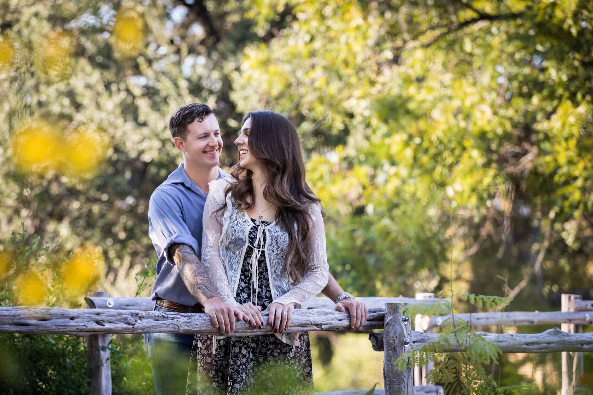 Couple hugging in front of wooden railing for an article on ‘Where do I Start with Wedding Planning?’