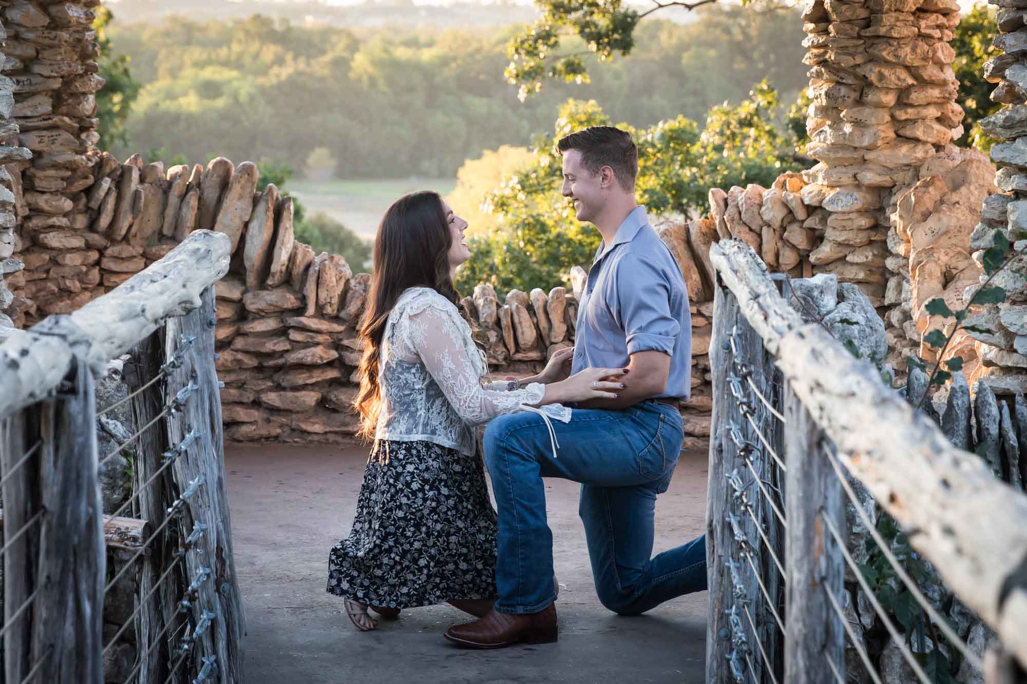 Man proposing on one knee to woman in middle of stone building during Japanese Tea Garden surprise proposal by Kelly Williams San Antonio wedding photographer