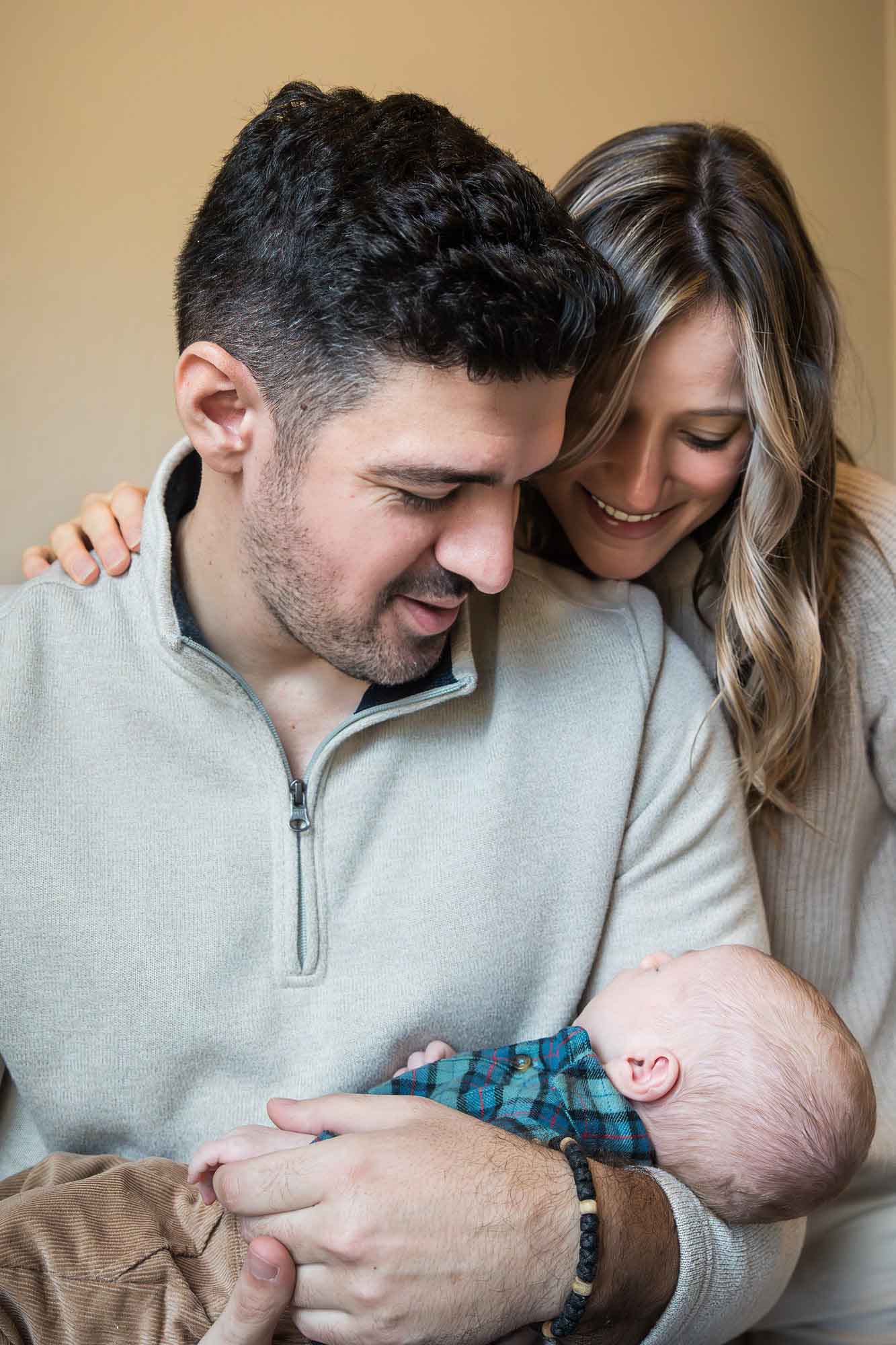 Mother and father holding baby boy wearing green and blue plaid shirt during an Austin newborn portrait session