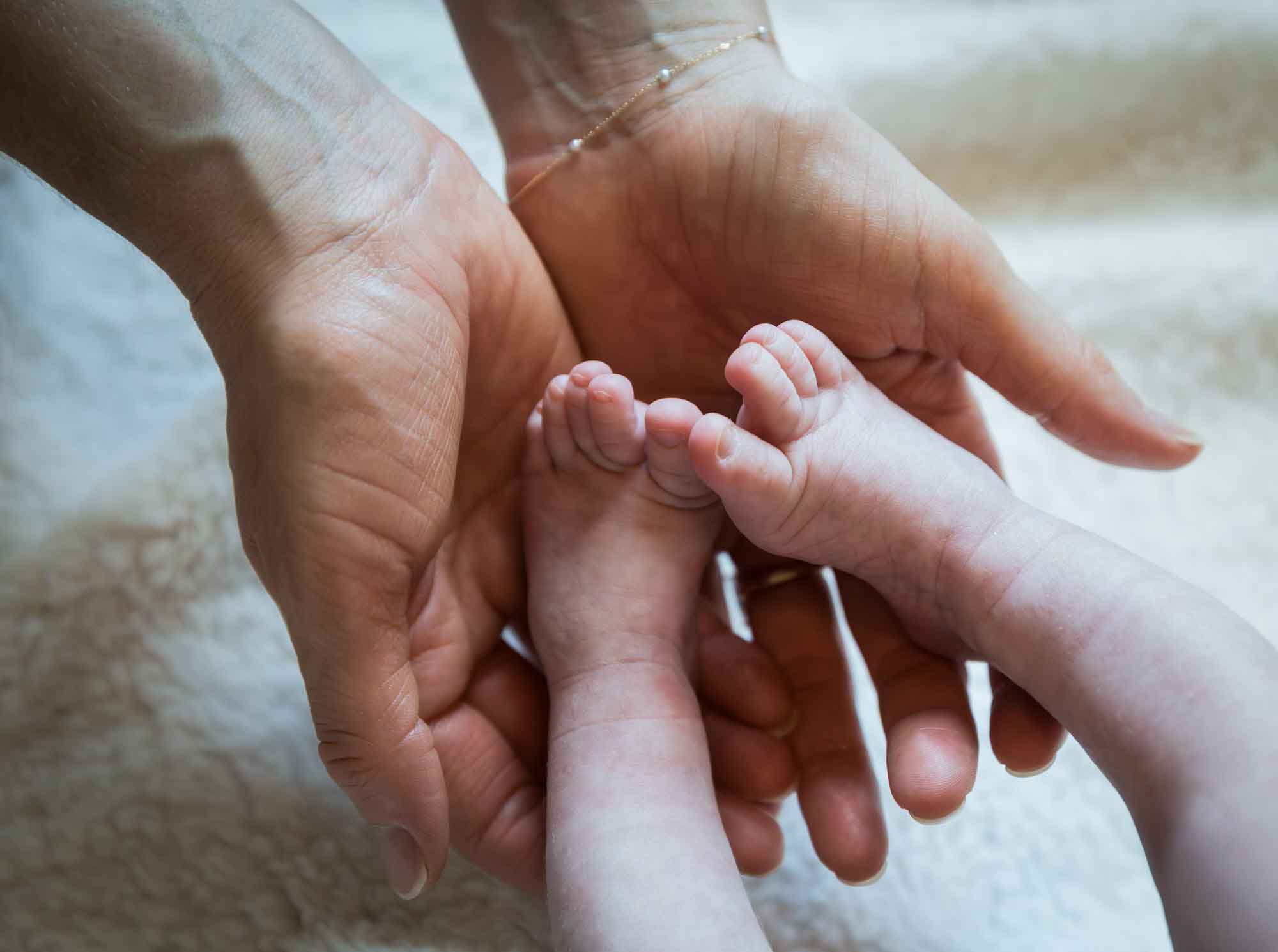 Close up of mother's hands holding feet of newborn baby boy
