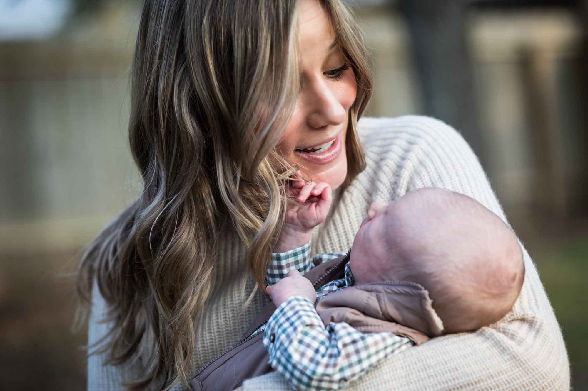 Mother smiling at newborn baby boy in backyard during an Austin newborn portrait session