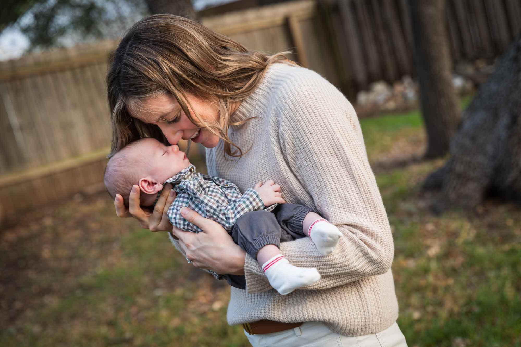 Mother holding newborn baby boy in backyard during an Austin newborn portrait session