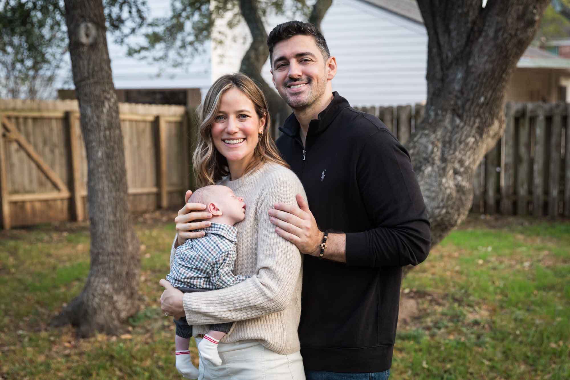 Mother and father holding newborn baby boy in backyard during an Austin newborn portrait session