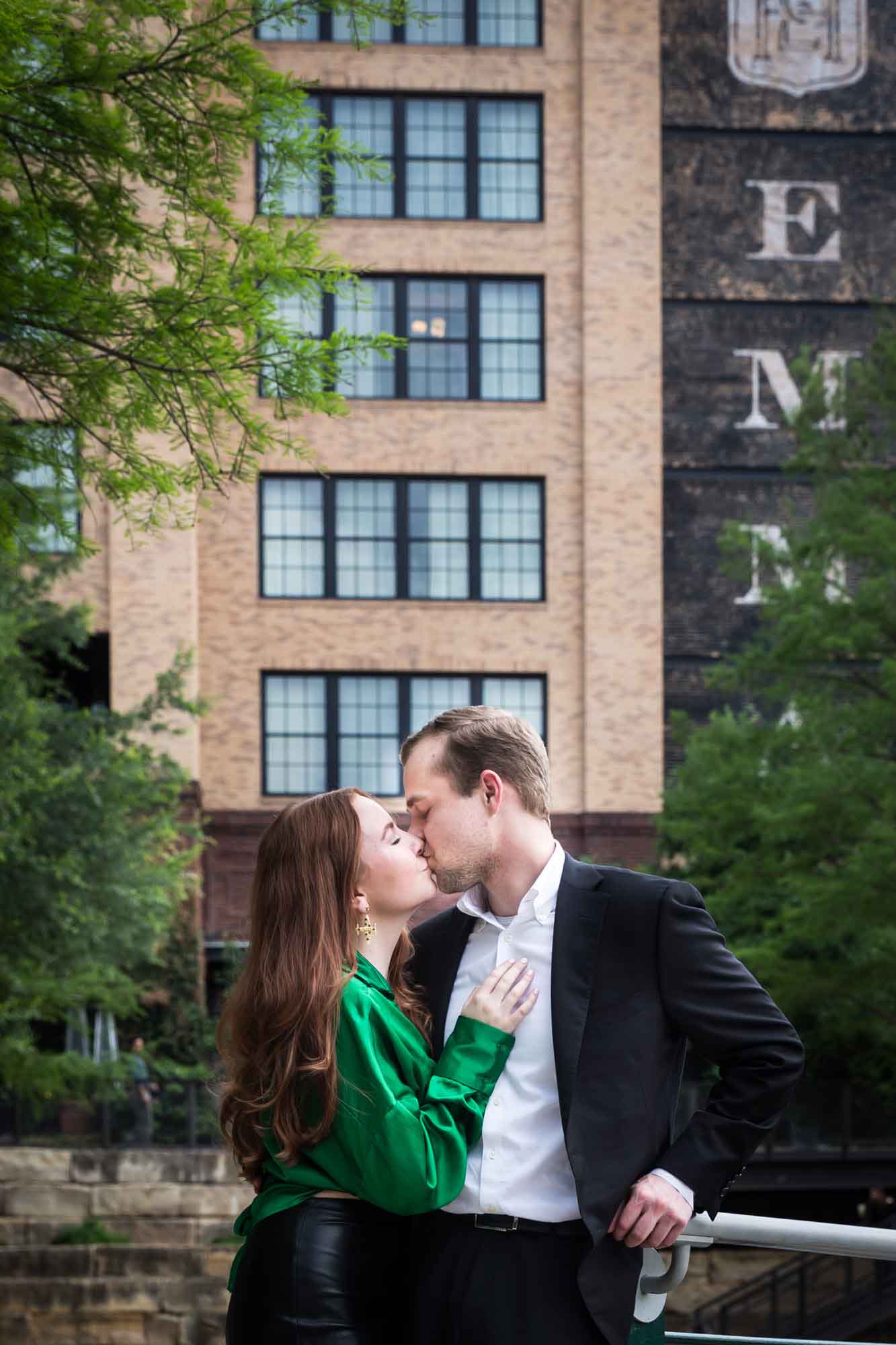 Man wearing black suit kissing woman wearing green blouse in front of Emma Hotel during an Emma Hotel surprise proposal