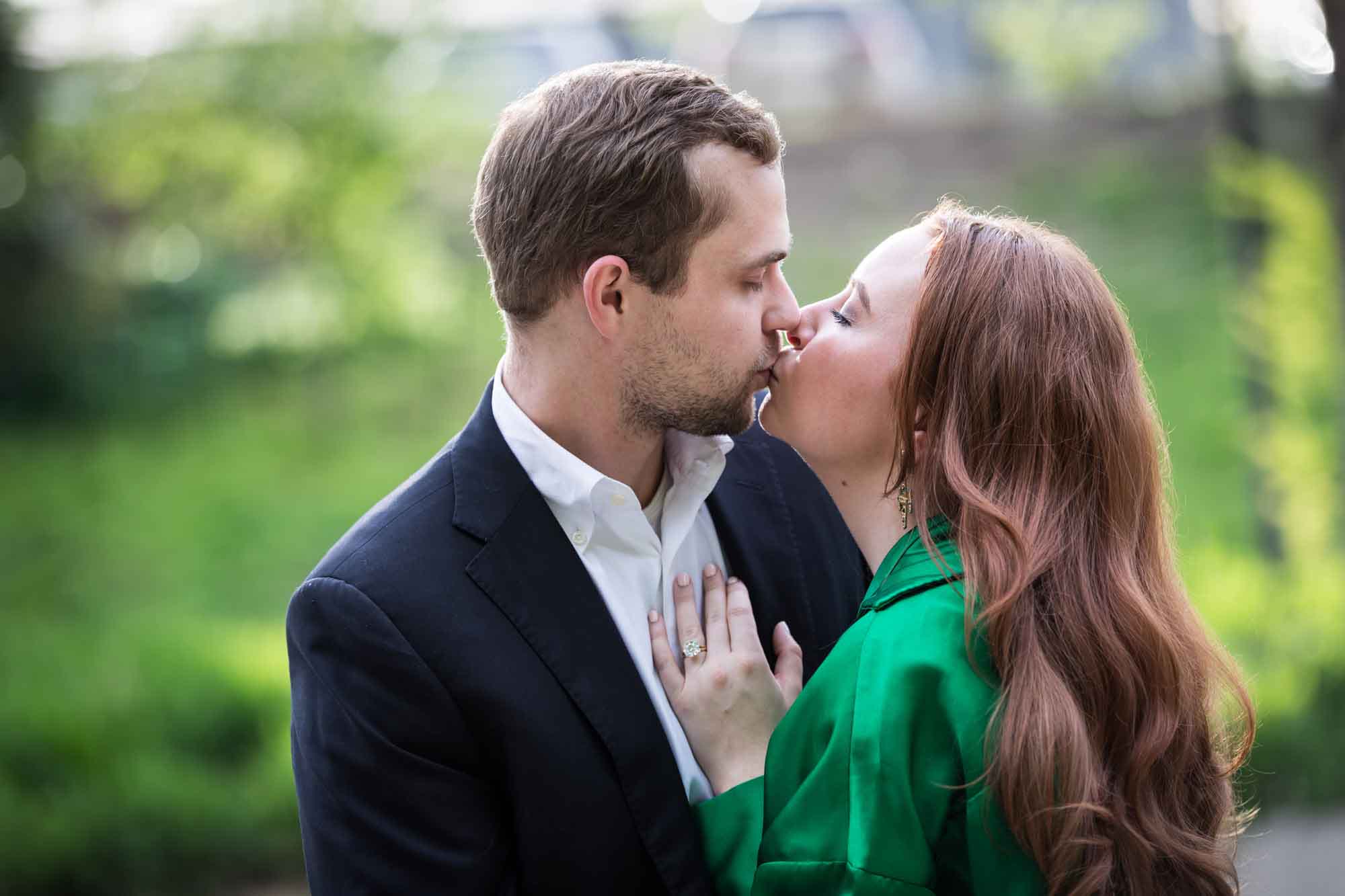 Man wearing black suit kissing woman wearing green blouse during an Emma Hotel surprise proposal