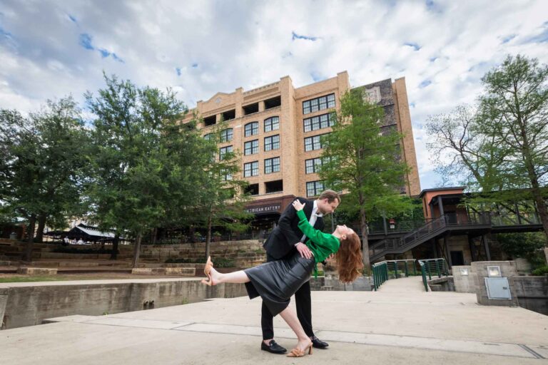 Man wearing black suit dipping woman wearing green blouse in front of Emma Hotel during an Emma Hotel proposal