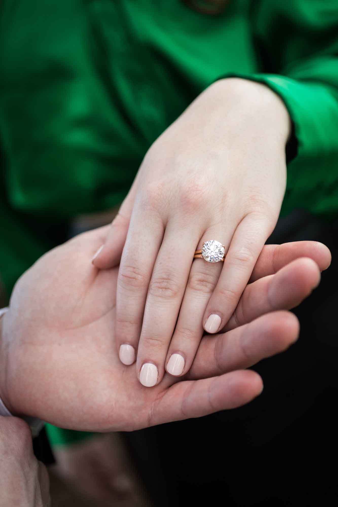 Close up of woman's hand showing engagement ring with her hand laid on man's hand