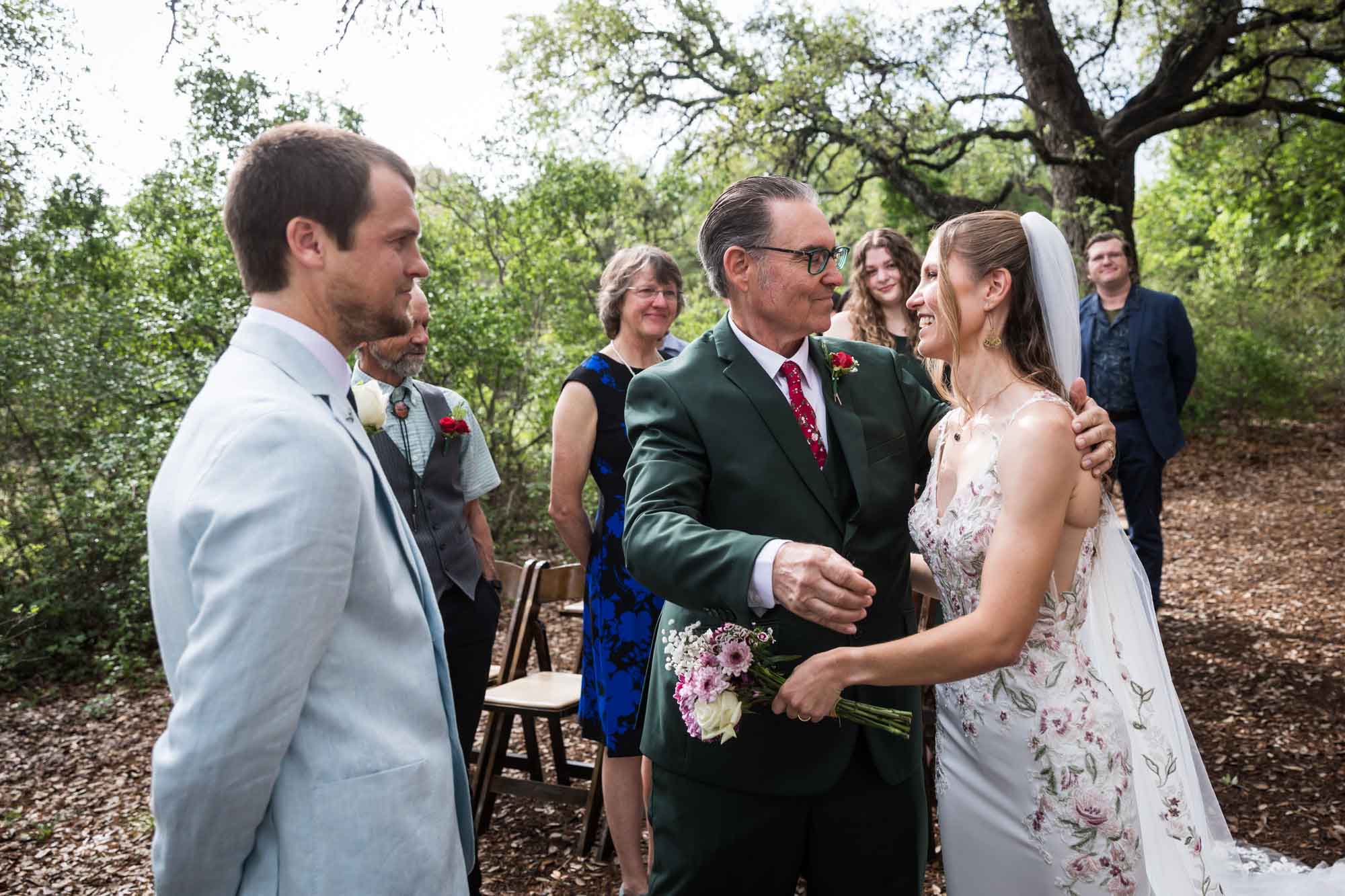 Father about to hug bride in front of groom and guests during ceremony during a Lady Bird Johnson Wildflower Center wedding