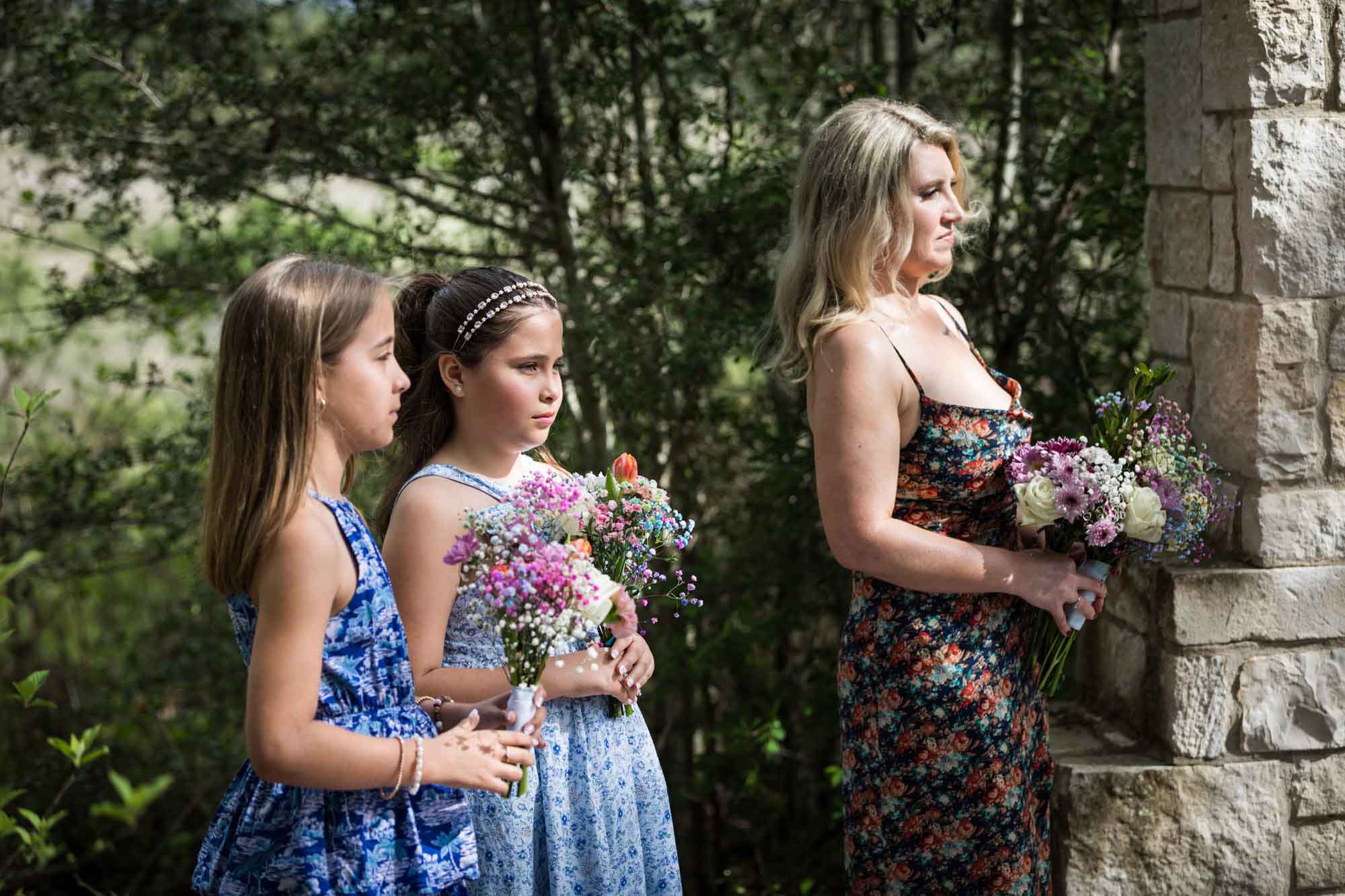 Maid of honor and two flower girls holding bouquets and standing during ceremony during a Lady Bird Johnson Wildflower Center wedding
