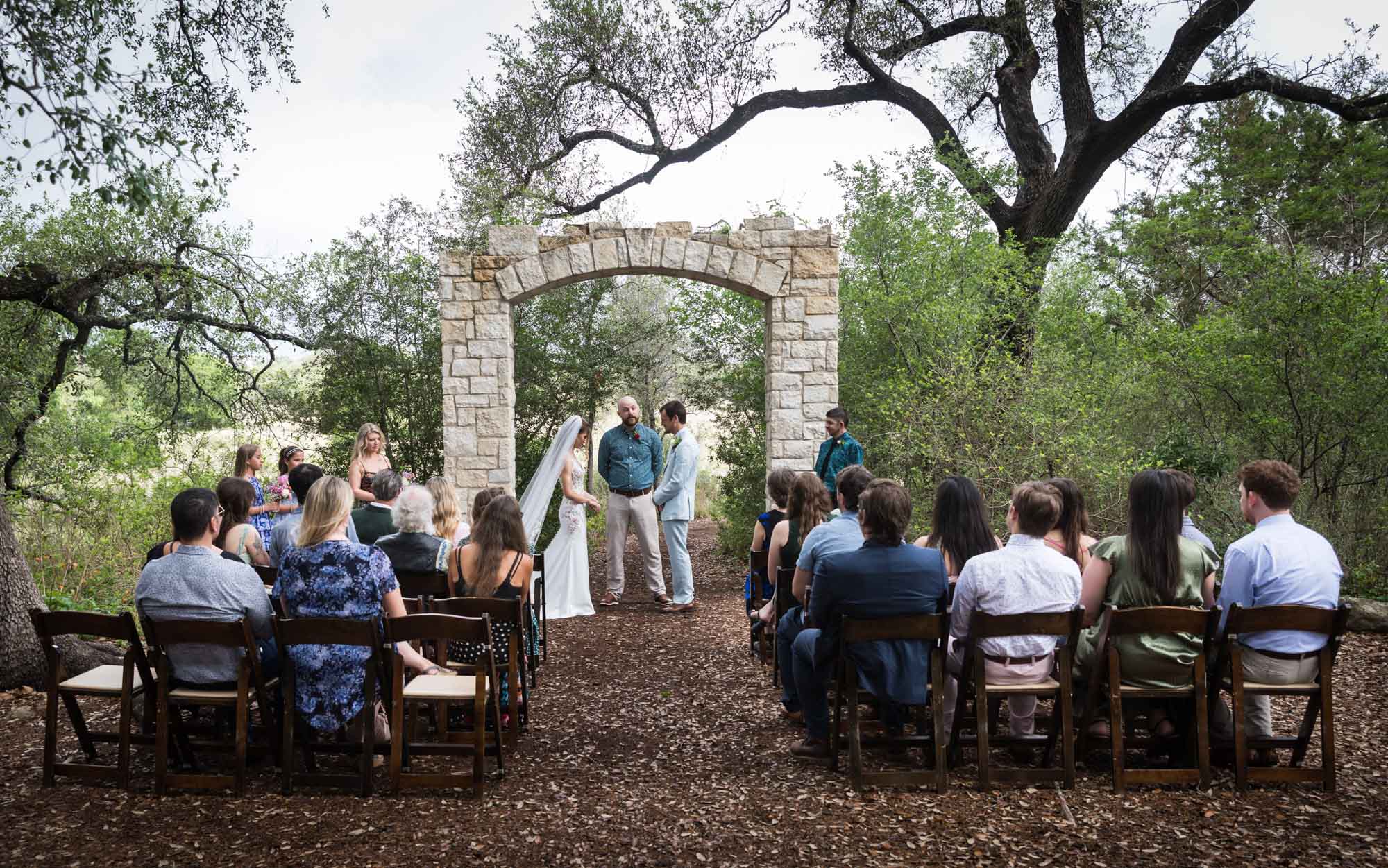 Wide shot of seated guests watching bride, groom and bridal party during ceremony at Cecille's Arch during a Lady Bird Johnson Wildflower Center wedding