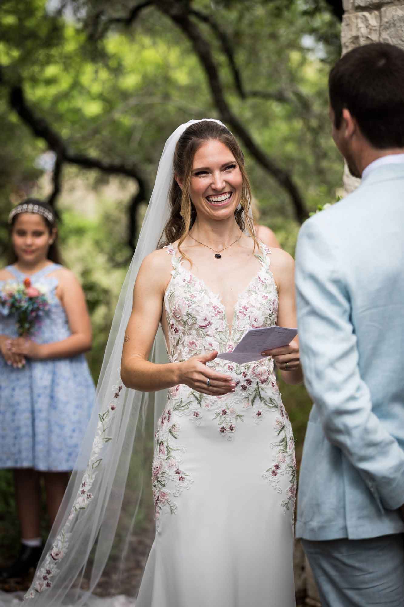 Bride reading vows to groom in front of flower girls during a Lady Bird Johnson Wildflower Center wedding