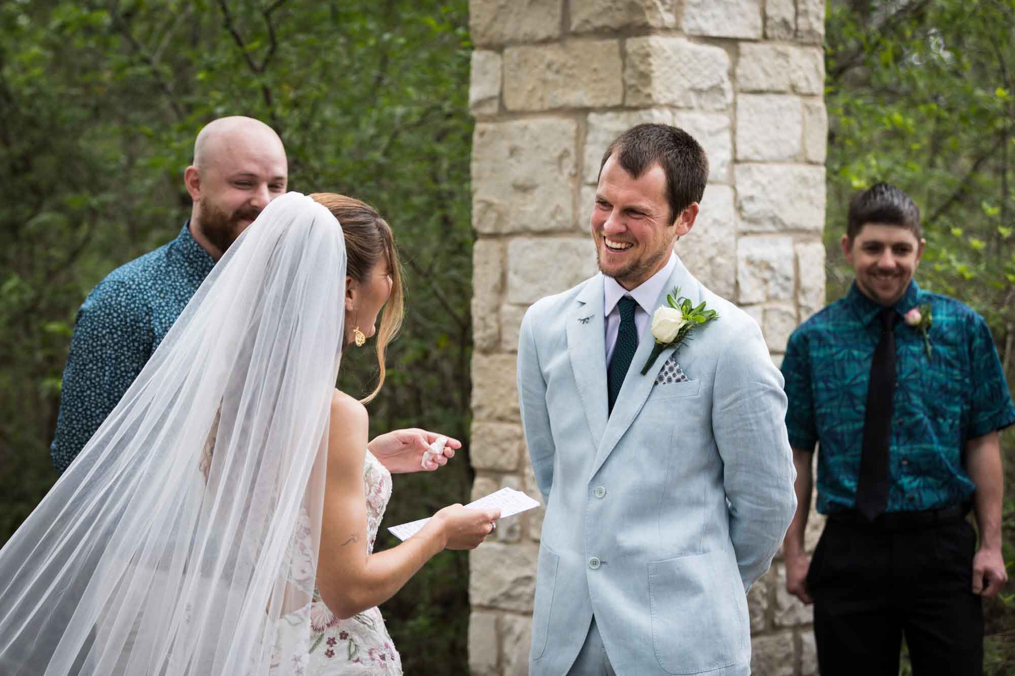 Bride reading vows to groom wearing light blue blazer in front of Cecille's Arch during a Lady Bird Johnson Wildflower Center wedding