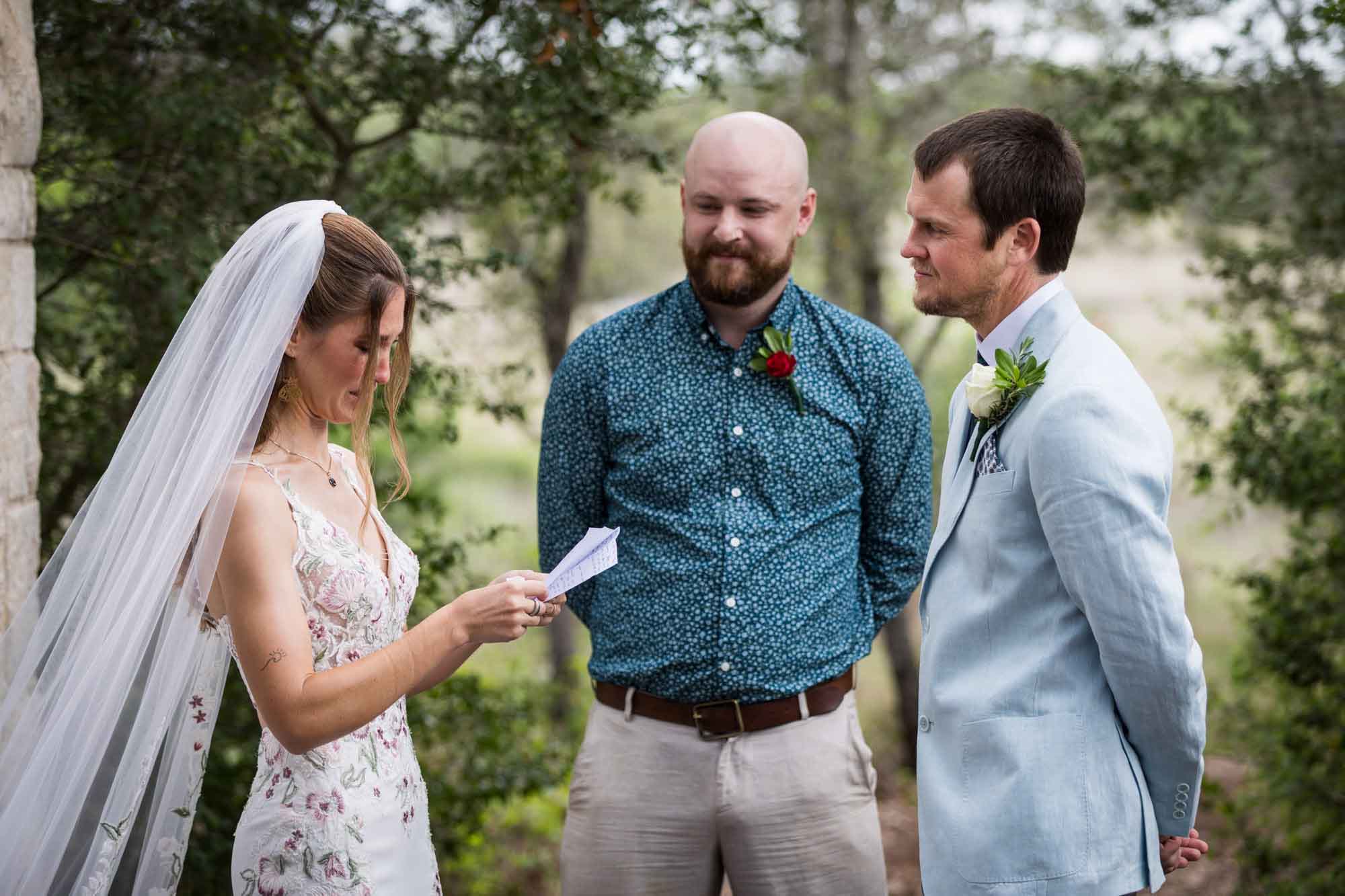 Bride reaching vows to groom in front of officiant at Cecille's Arch during a Lady Bird Johnson Wildflower Center wedding