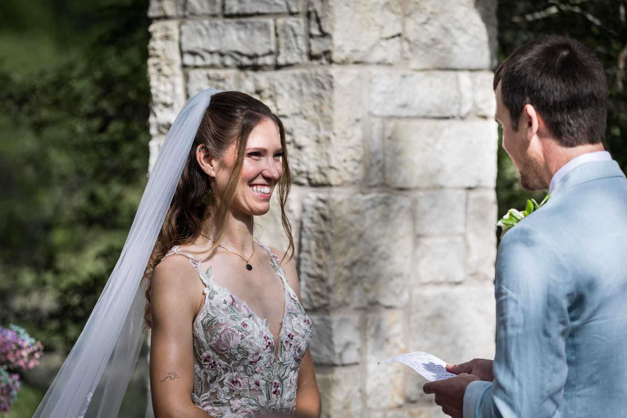 Bride watching groom read vows at Cecille's Arch during a Lady Bird Johnson Wildflower Center wedding