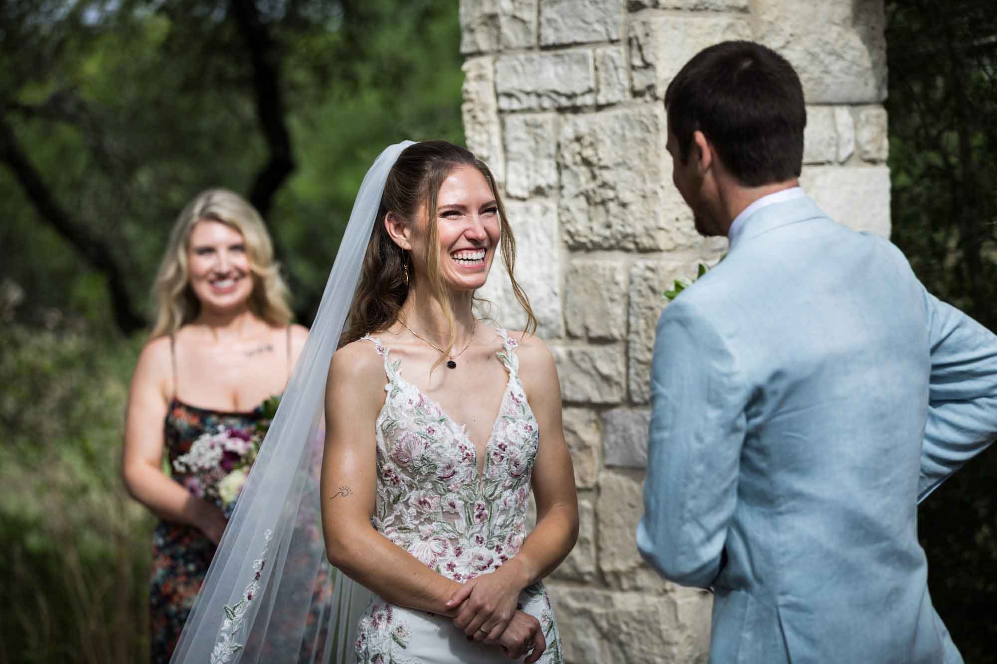 Bride watching groom read vows at Cecille's Arch during a Lady Bird Johnson Wildflower Center wedding