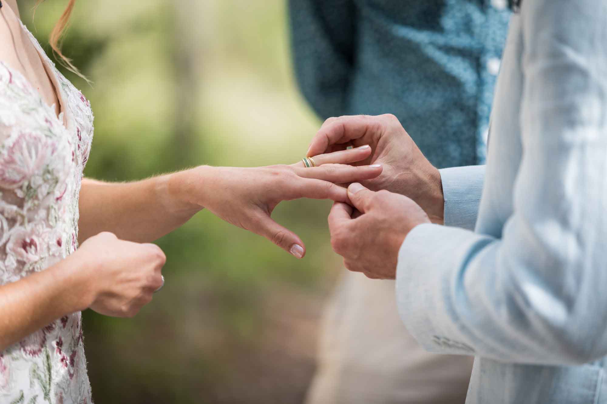 Close up of groom put wedding ring on bride's finger during a Lady Bird Johnson Wildflower Center wedding