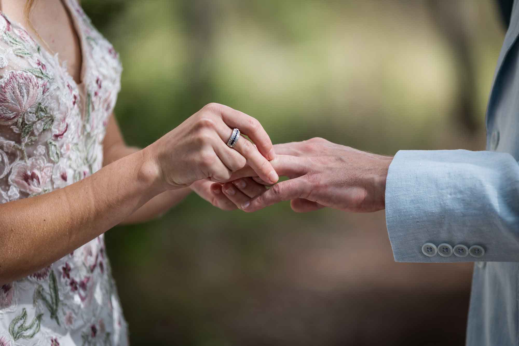 Close up of bride putting wedding ring on groom's finger during a Lady Bird Johnson Wildflower Center wedding
