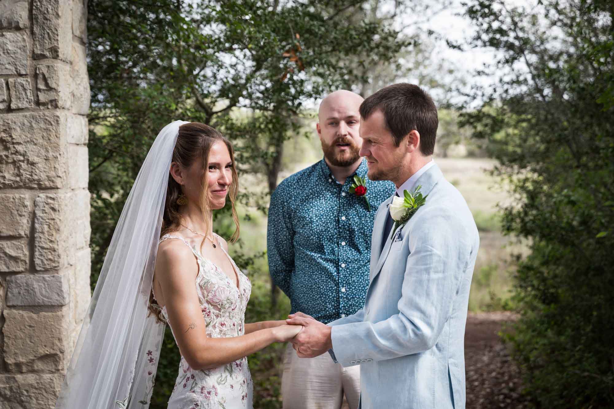 Groom looking at bride as they hold hands in front of officiant during a Lady Bird Johnson Wildflower Center wedding