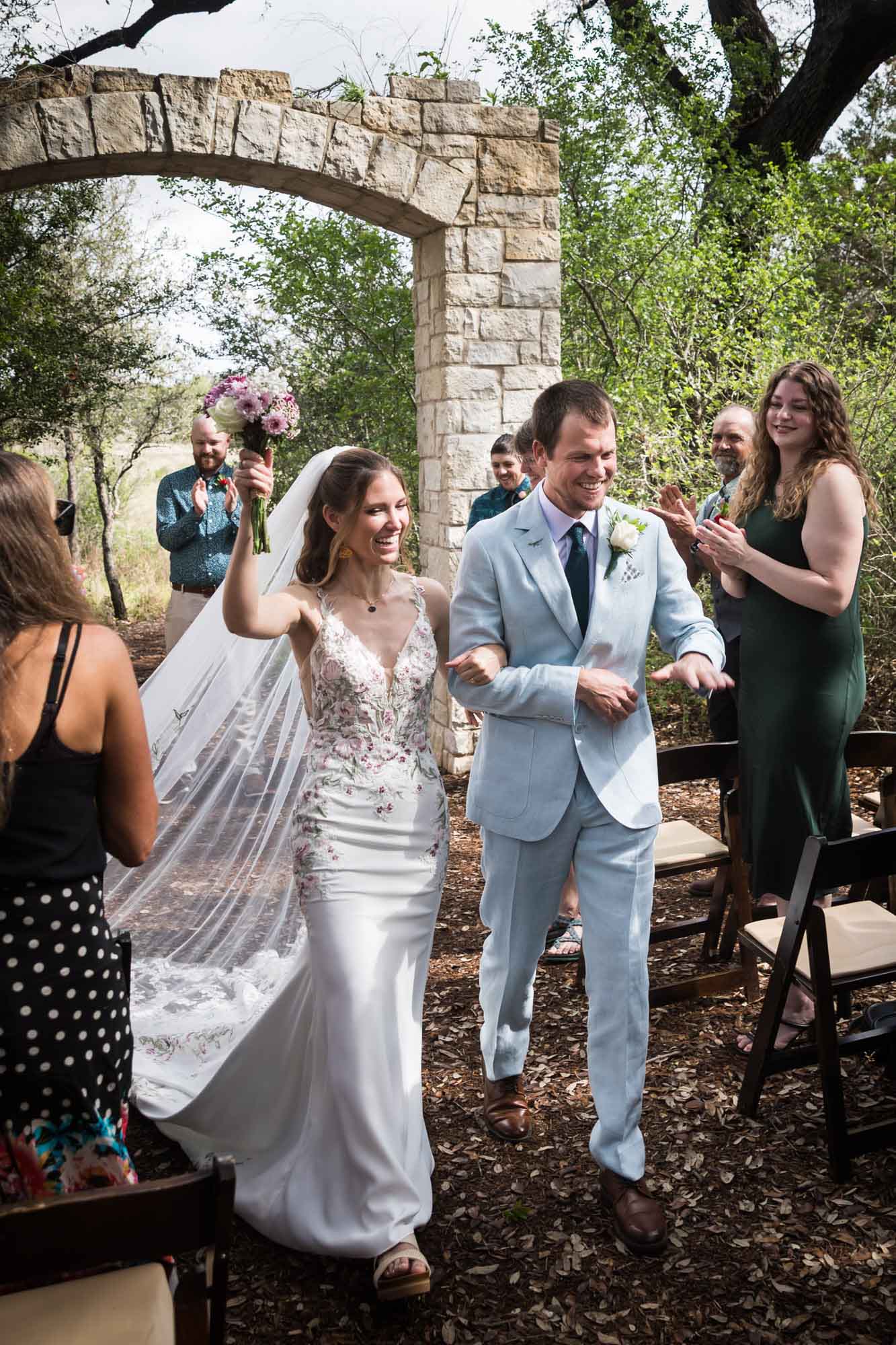 Bride and groom cheering in front of guests as they proceed down aisle after ceremony during a Lady Bird Johnson Wildflower Center wedding