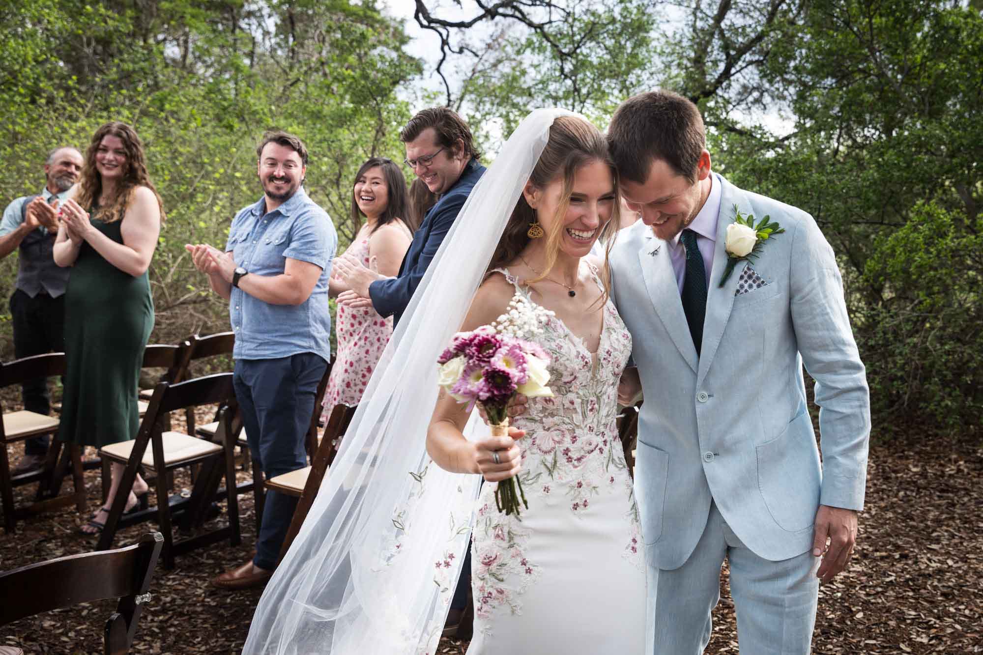 Bride and groom standing with heads pressed together in front of guests after ceremony during a Lady Bird Johnson Wildflower Center wedding