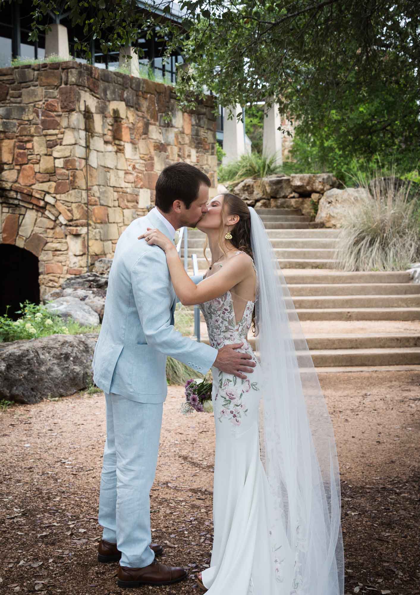 Bride and groom kissing in front of Savanna Meadow stairs during a Lady Bird Johnson Wildflower Center wedding