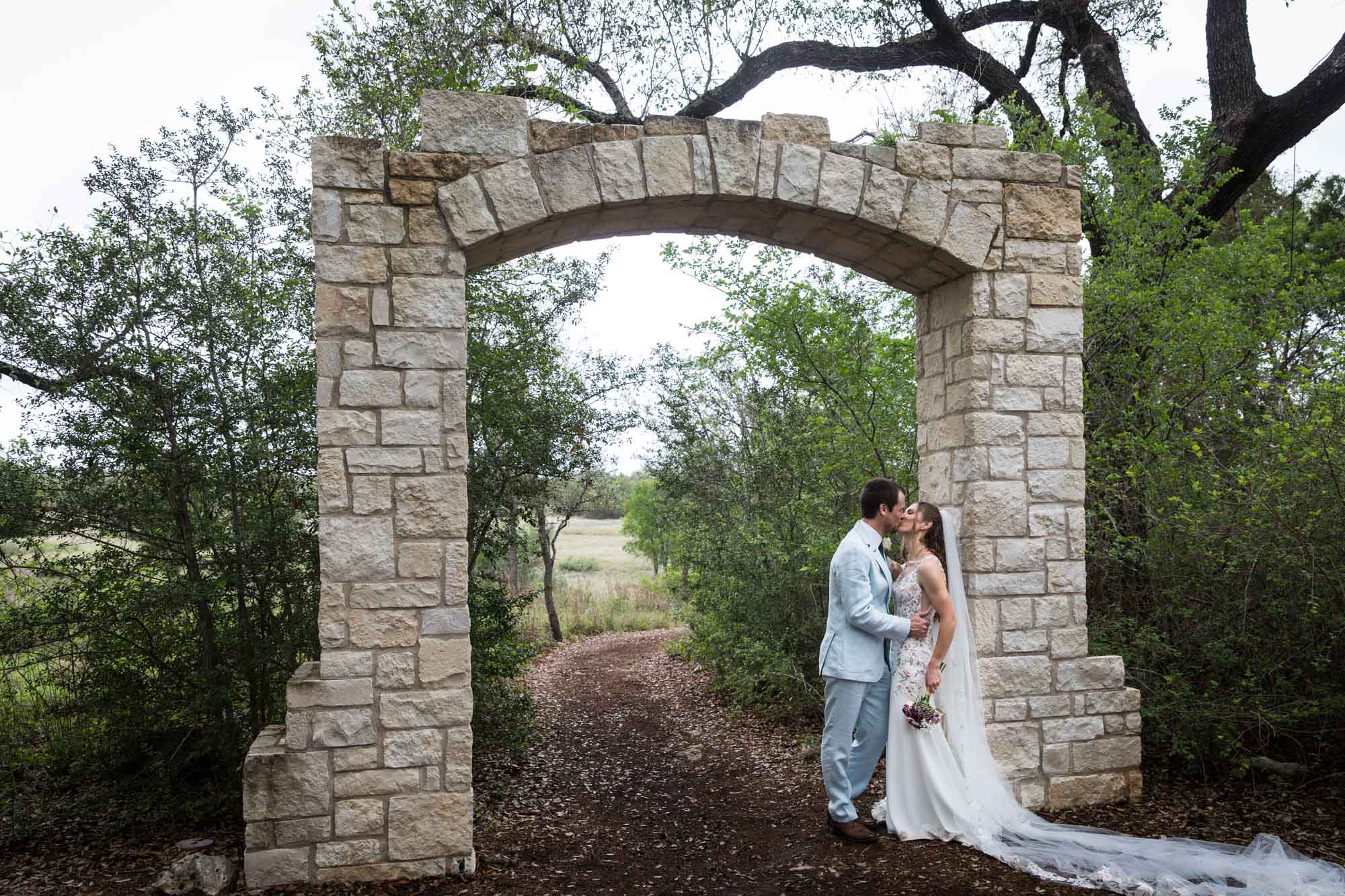 Lady Bird Johnson Wildflower Center wedding photos of bride and groom leaning against Cecille's Arch