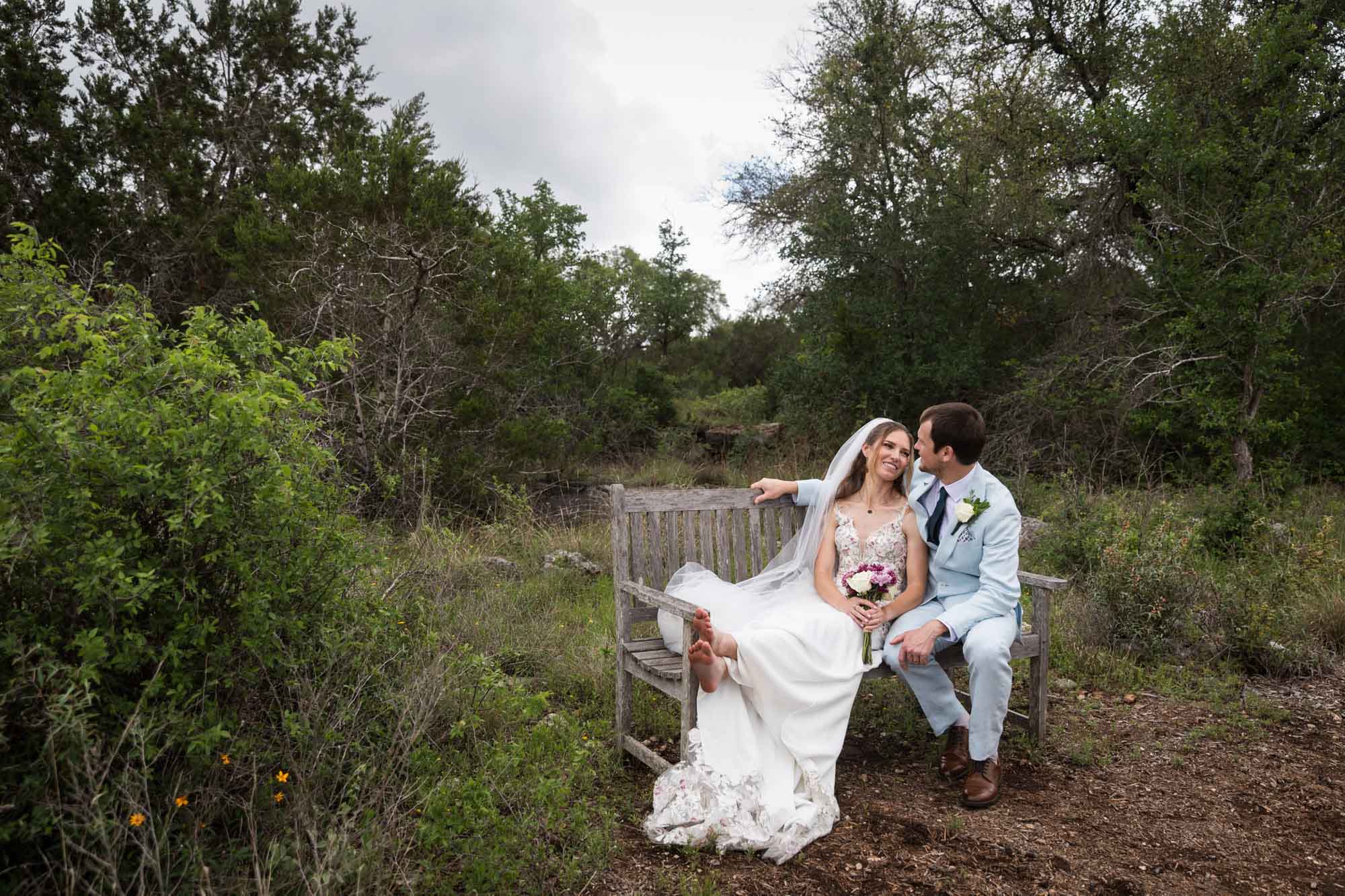 Lady Bird Johnson Wildflower Center wedding photos of a bride and groom seated on wooden bench in middle of Savanna Meadow