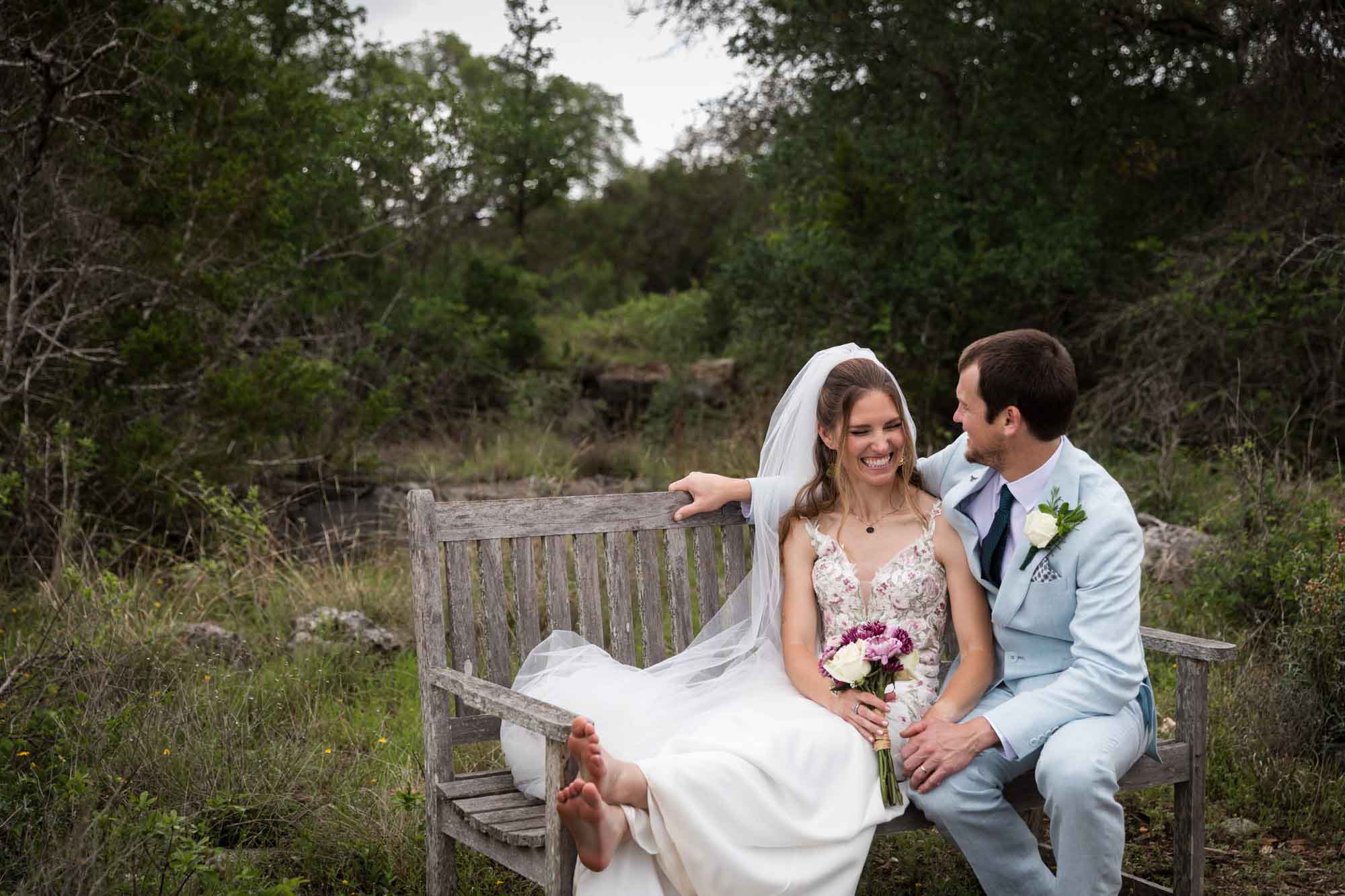 Lady Bird Johnson Wildflower Center wedding photos of a bride and groom seated on wooden bench in middle of Savanna Meadow