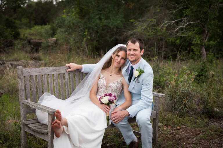 Lady Bird Johnson Wildflower Center wedding photos of a bride and groom seated on wooden bench in middle of Savanna Meadow