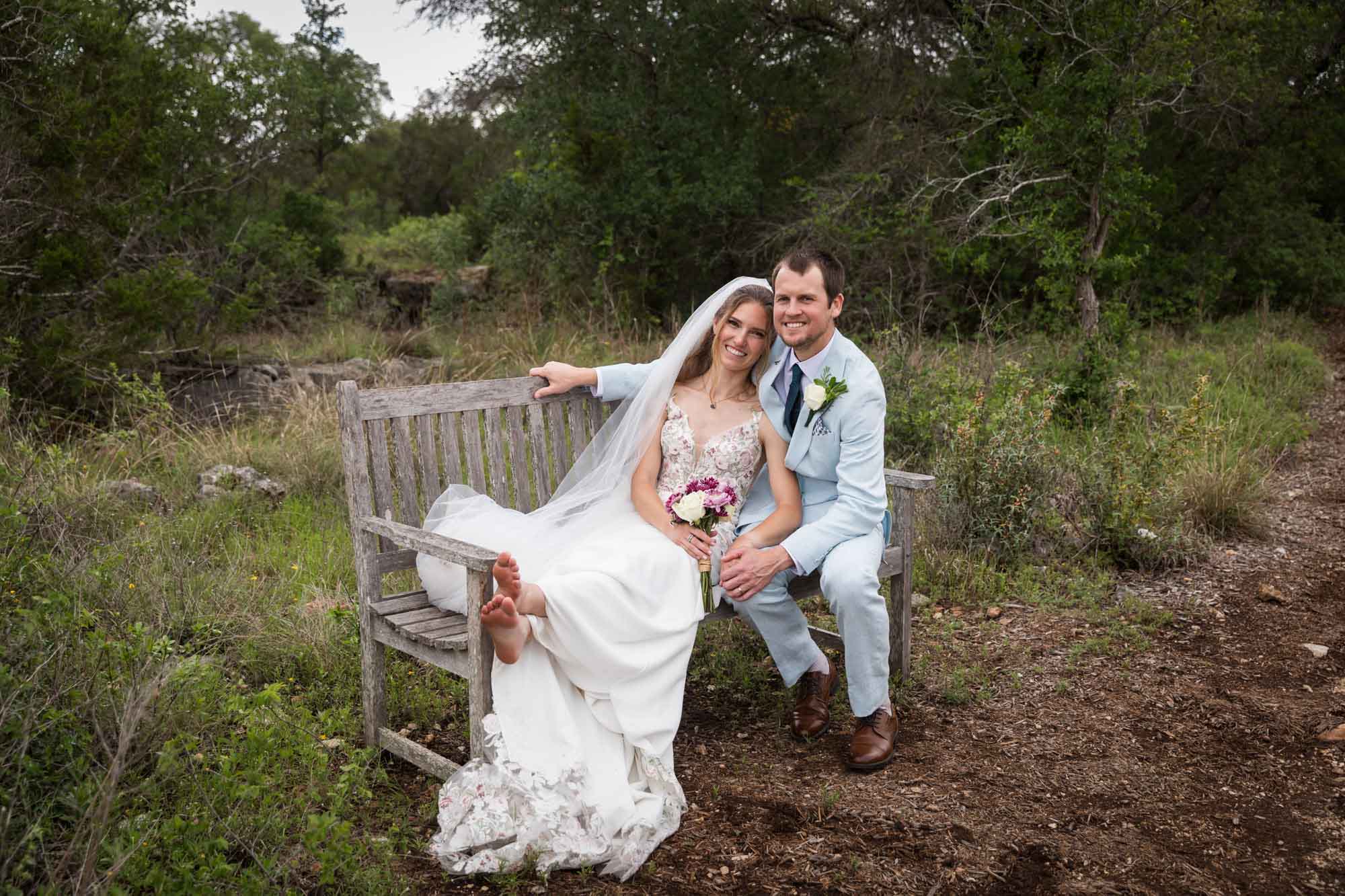 Lady Bird Johnson Wildflower Center wedding photos of a bride and groom seated on wooden bench in middle of Savanna Meadow
