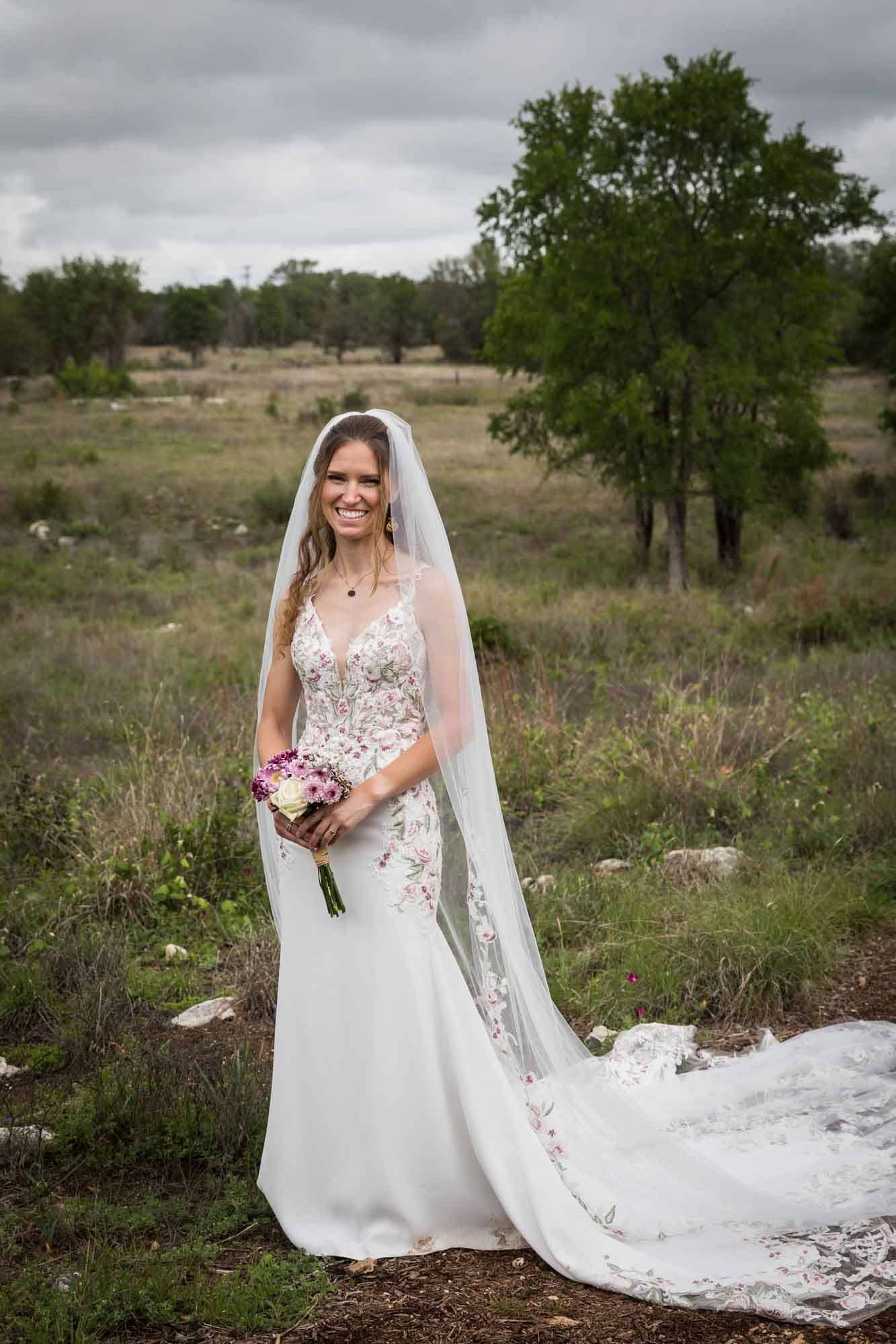 Lady Bird Johnson Wildflower Center wedding photos of a bride standing holding flower bouquet in middle of Savanna Meadow