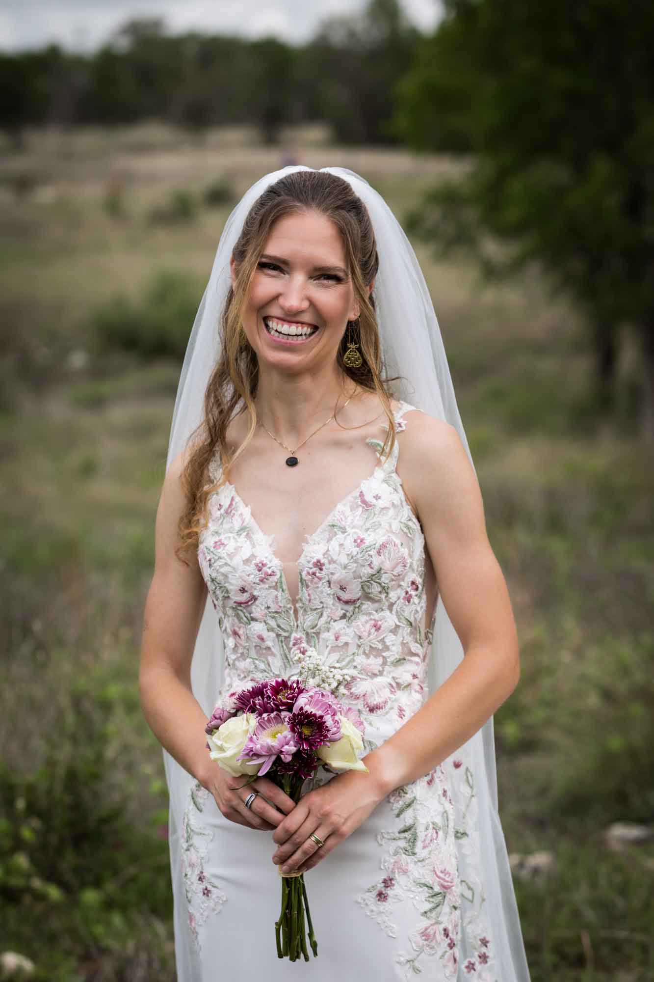 Lady Bird Johnson Wildflower Center wedding photos of a bride standing holding flower bouquet in middle of Savanna Meadow