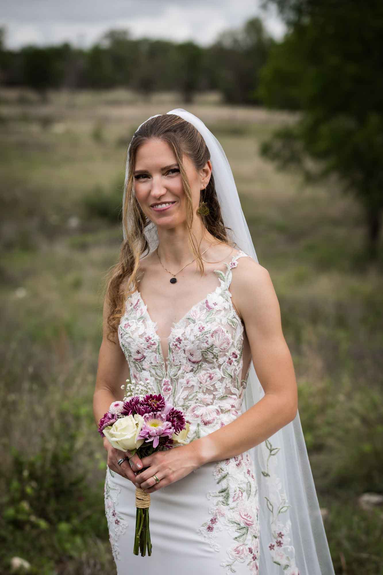 Lady Bird Johnson Wildflower Center wedding photos of a bride standing holding flower bouquet in middle of Savanna Meadow