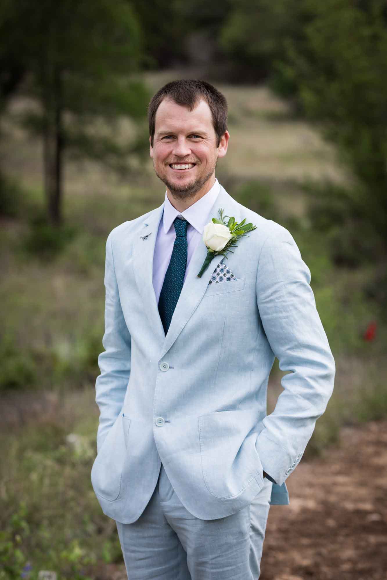 Lady Bird Johnson Wildflower Center wedding photos of a groom wearing light blue blazer in middle of Savanna Meadow