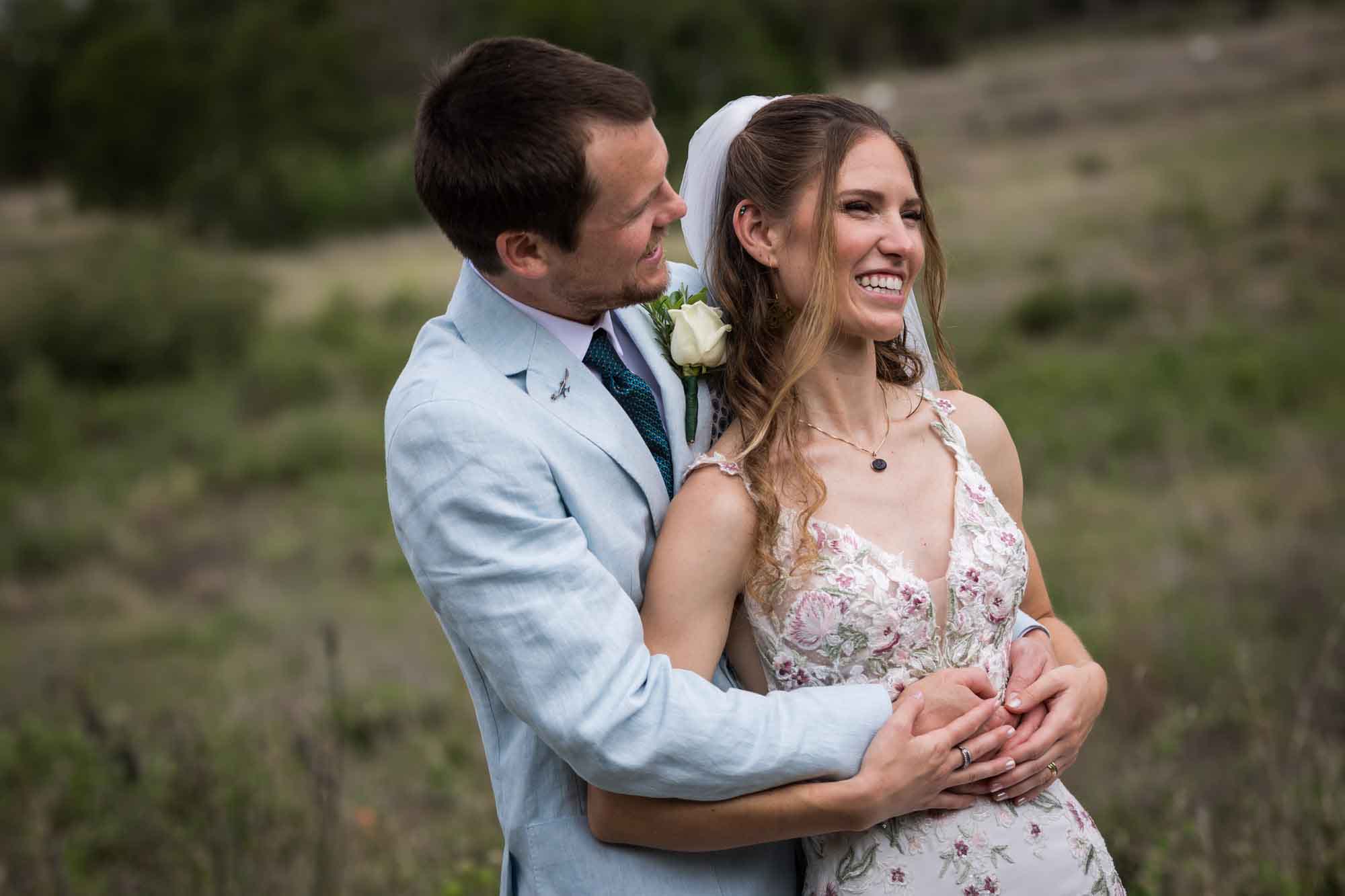 Lady Bird Johnson Wildflower Center wedding photos of a bride and groom hugging and laughing in middle of Savanna Meadow