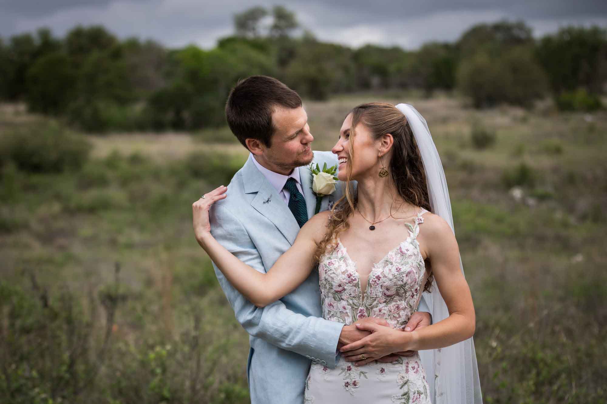 Lady Bird Johnson Wildflower Center wedding photos of a bride and groom hugging and laughing in middle of Savanna Meadow