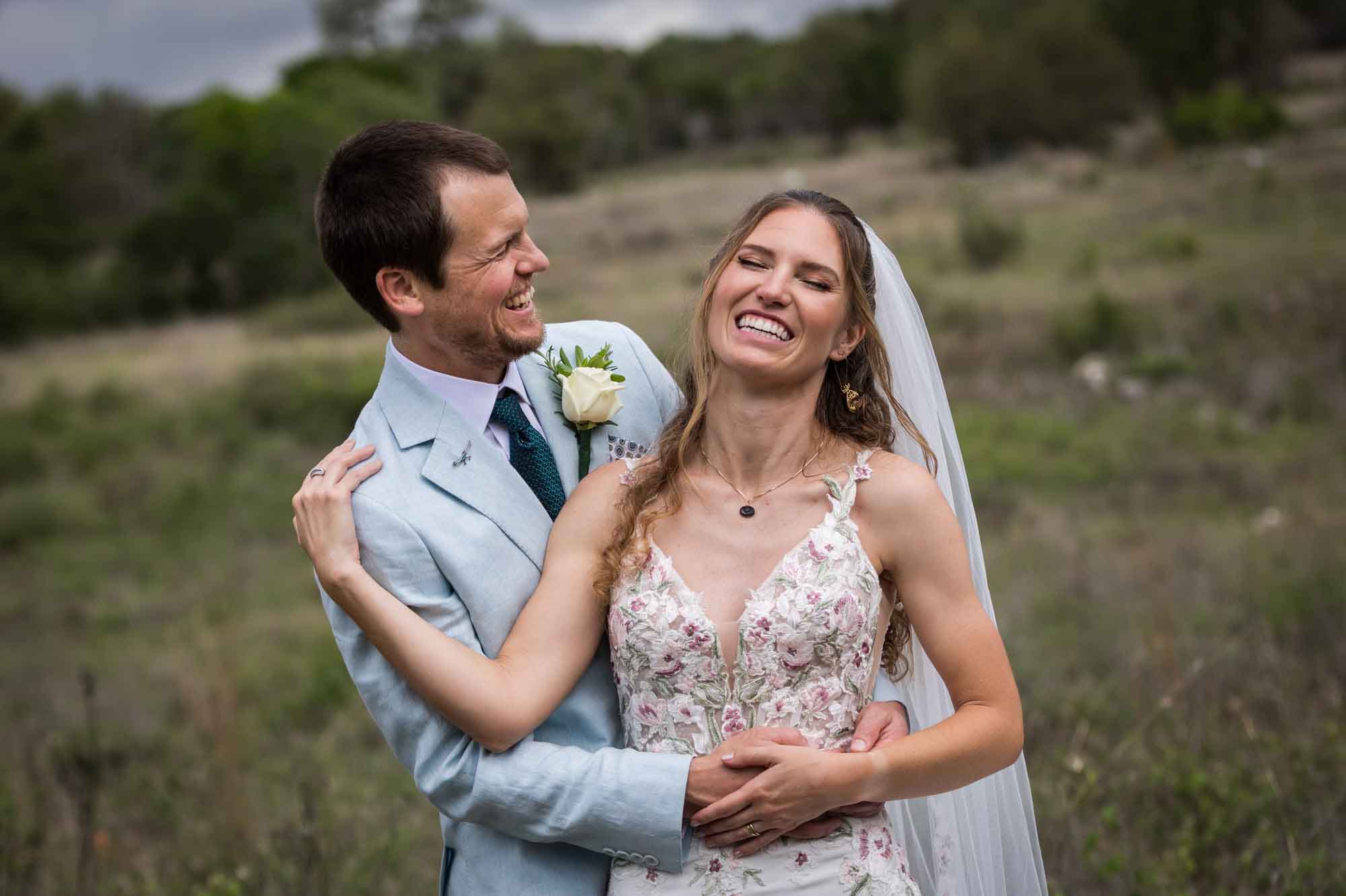 Lady Bird Johnson Wildflower Center wedding photos of a bride and groom hugging and laughing in middle of Savanna Meadow